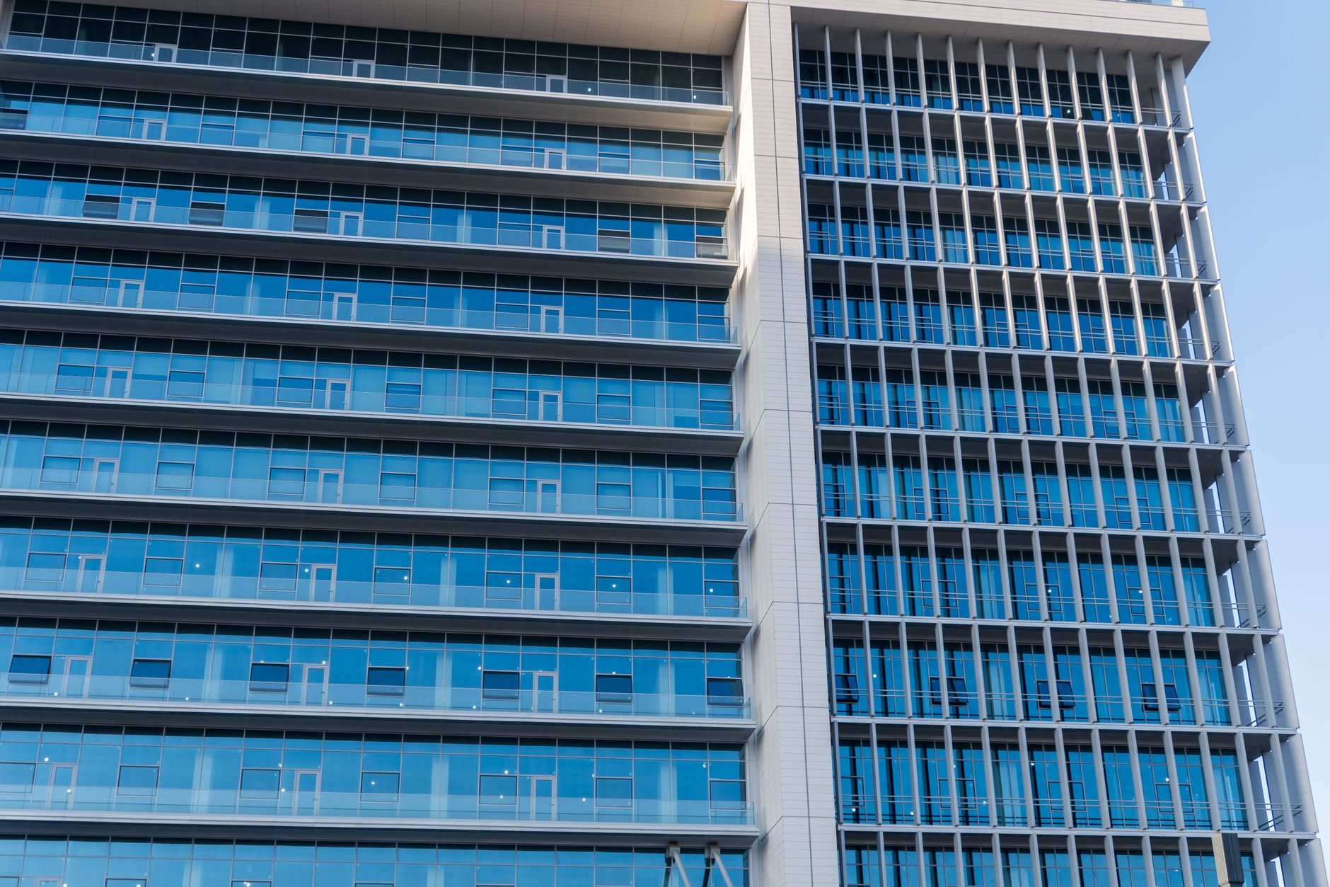 exterior of a modern multi-story hospital dialysis center building with floor-to-ceiling glass windows and medical facility signage, photographed at midday