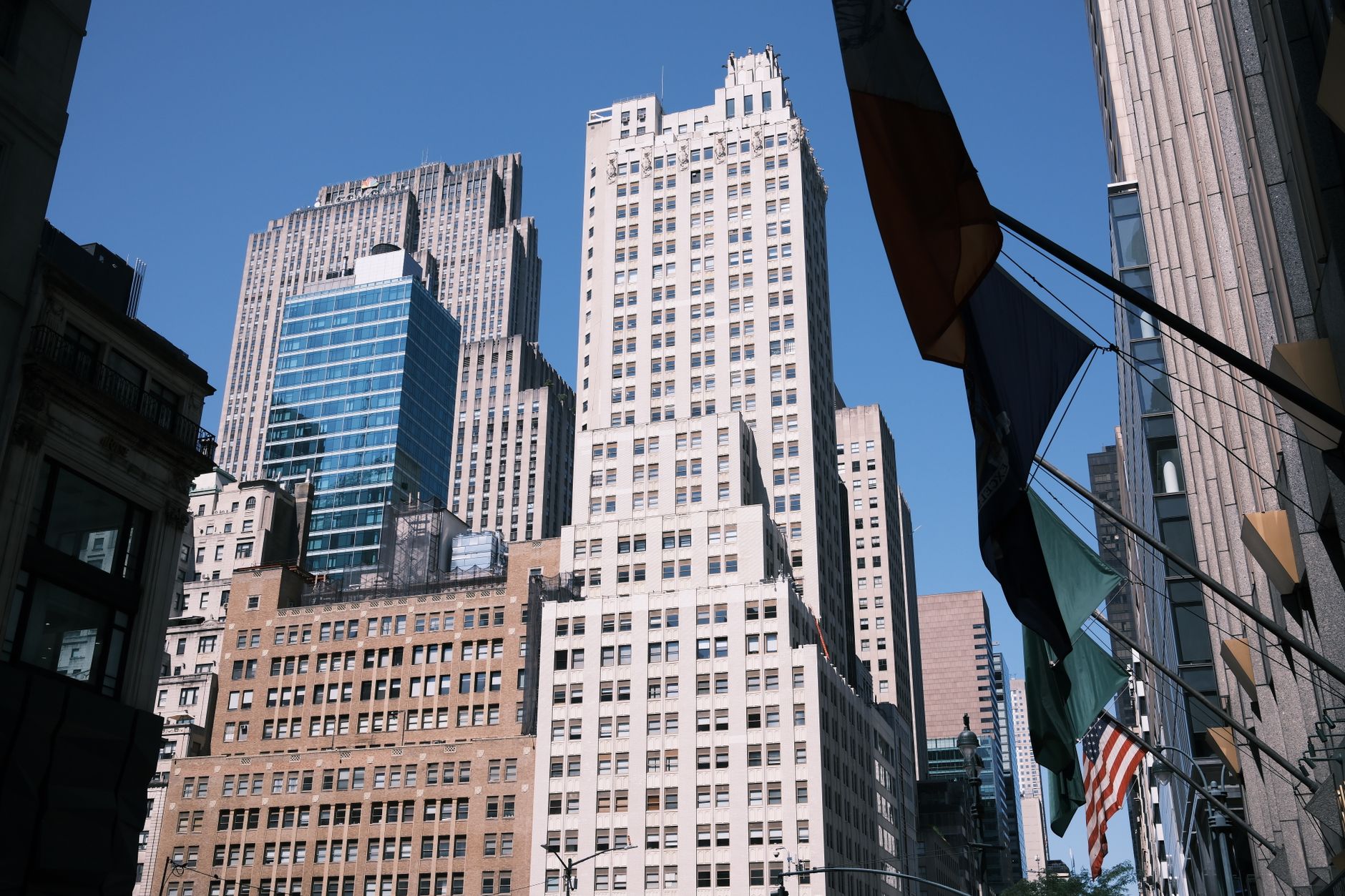 exterior of the New York Stock Exchange building on a quiet summer morning, flags visible against a pale sky