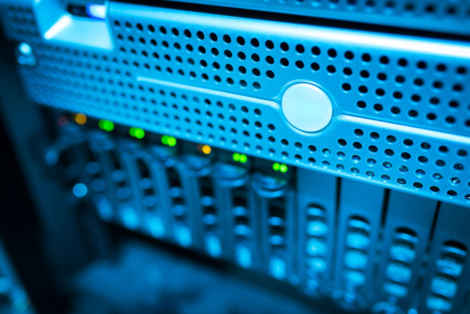 rows of server rack hardware inside a large data center facility, with blue LED lighting illuminating cable management systems along the aisles