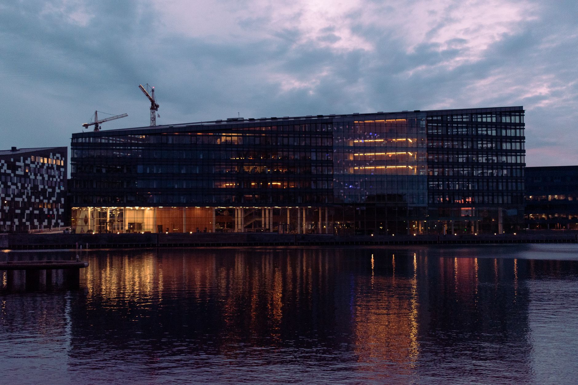 exterior of a technology research complex at dusk, with glass facades reflecting evening light and satellite dishes visible on the rooftop