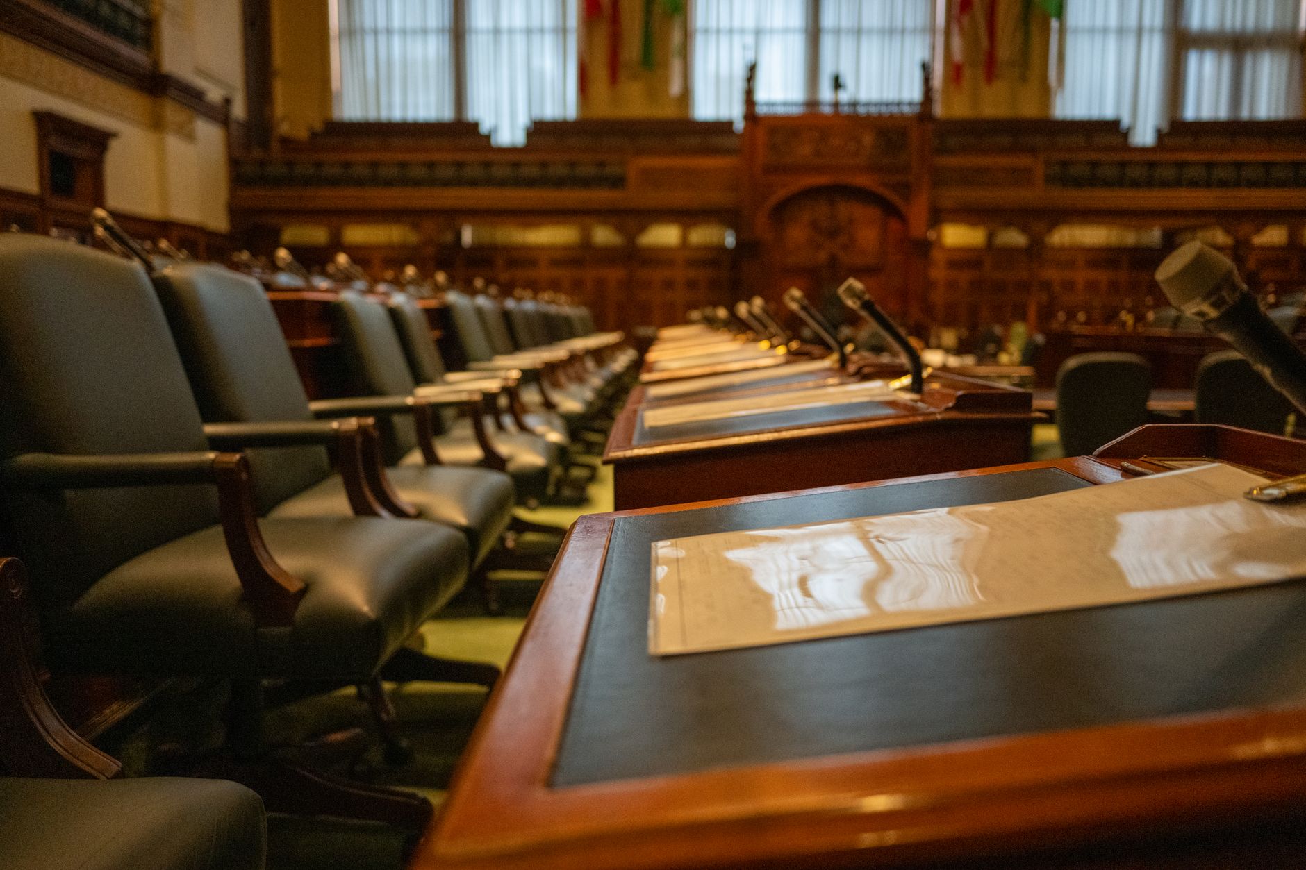 interior of an empty congressional hearing room with rows of leather chairs and a curved dais under fluorescent lighting