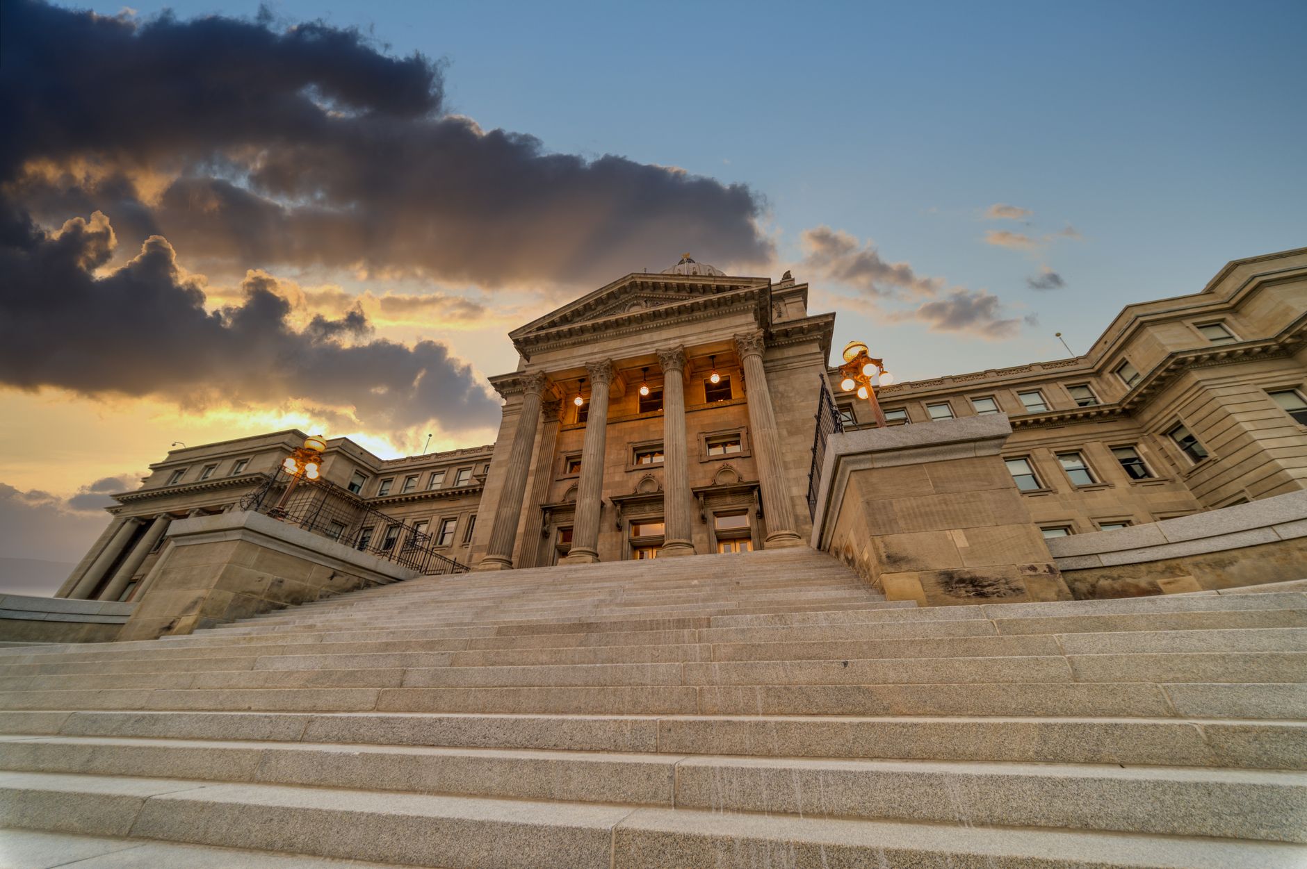 exterior of a state capitol building at midday with empty steps and a clear sky overhead
