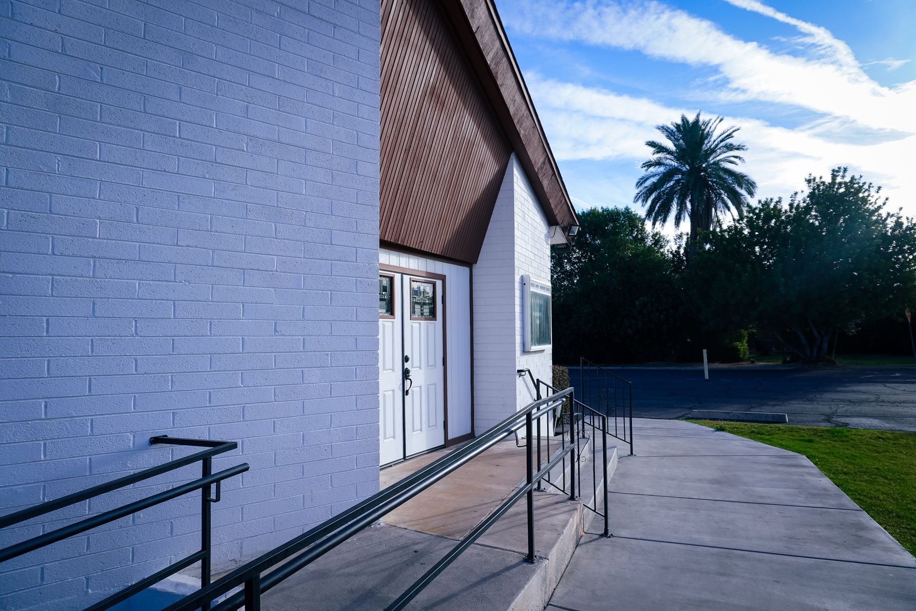 exterior of a modern cancer treatment and research facility in a Florida suburban setting, palm trees visible along a wide entrance pathway