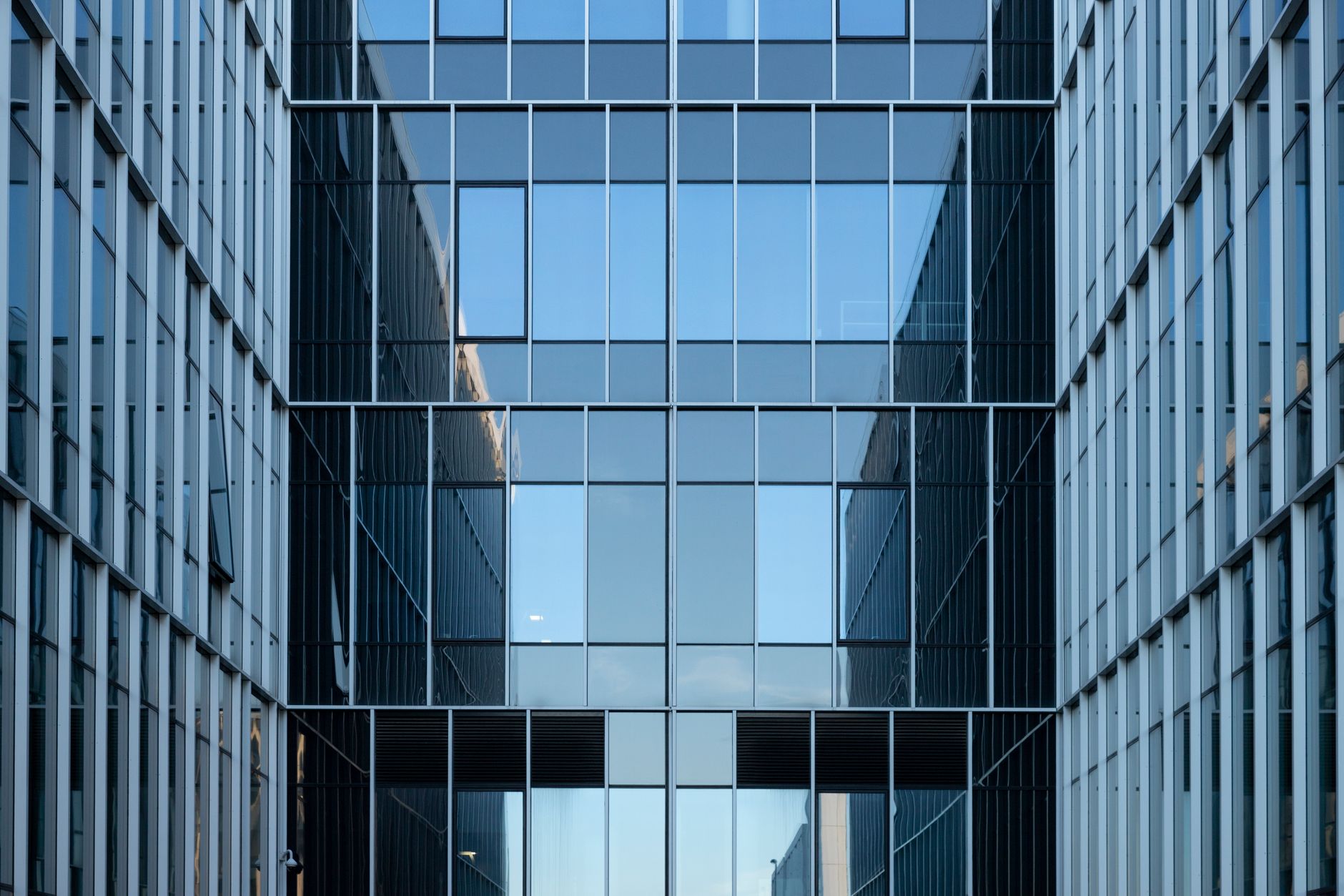 exterior view of a modern commercial office building in Tel Aviv's technology district at midday, with glass facades reflecting the surrounding skyline