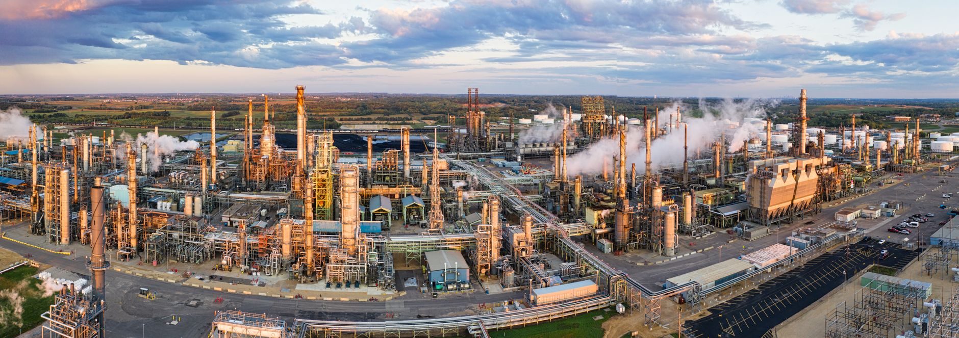 aerial view of oil and gas royalty land with pump jacks spread across flat prairie terrain at golden hour