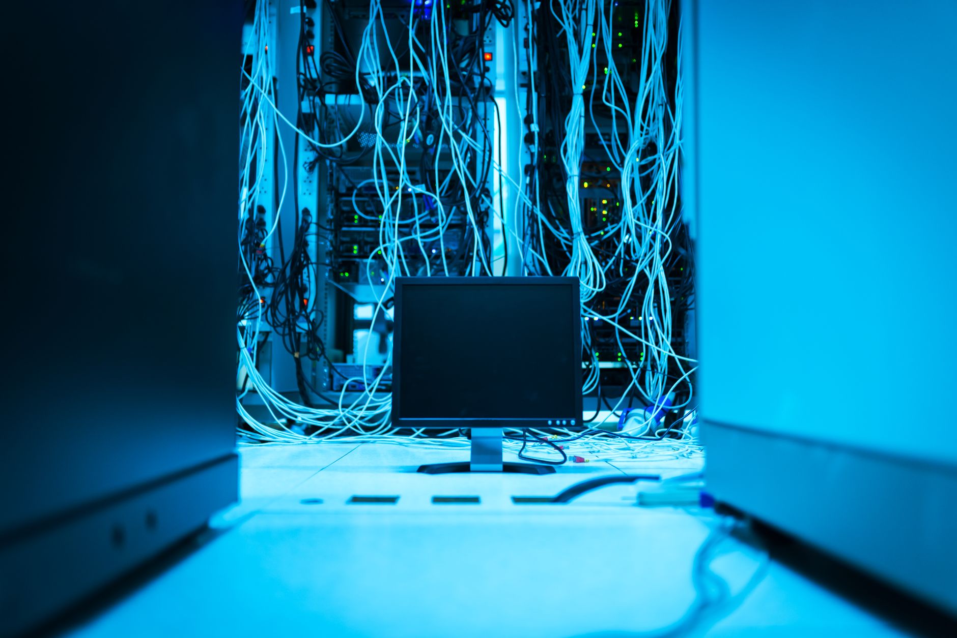 a wide-angle interior view of a large-scale server farm filled with rows of illuminated hardware racks in cool blue lighting