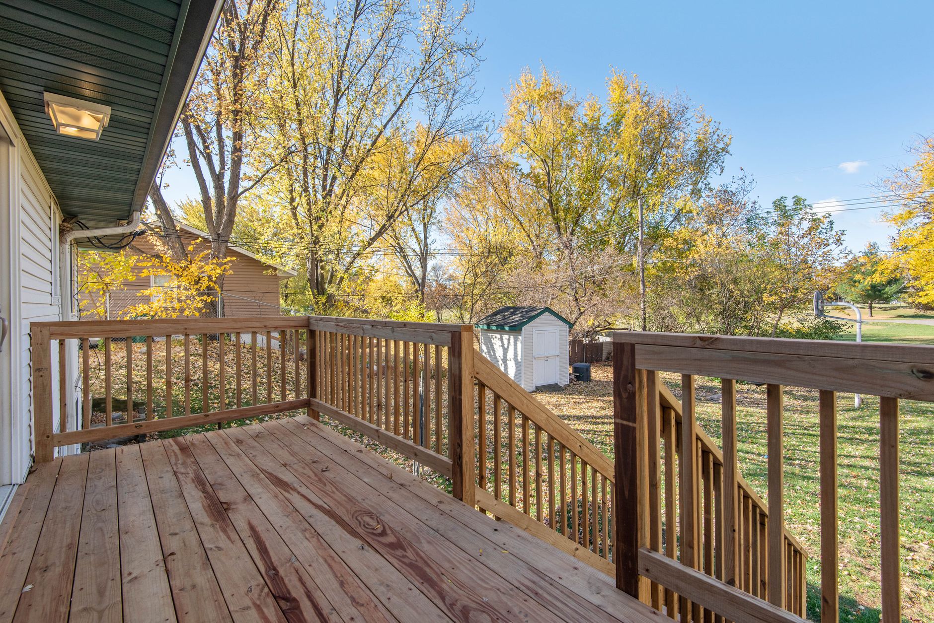 a compact two-bedroom prefabricated backyard unit installed on a suburban residential lot, surrounded by a timber deck and landscaped garden beds