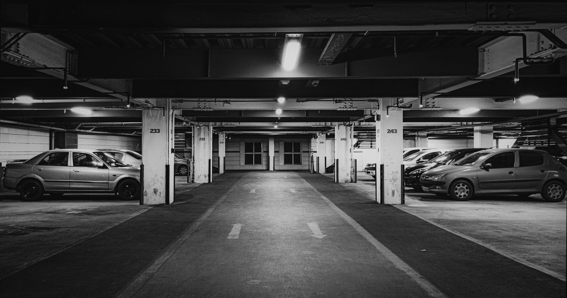 interior of a rental car return facility with vehicles lined up under fluorescent lighting, a service counter visible in the background