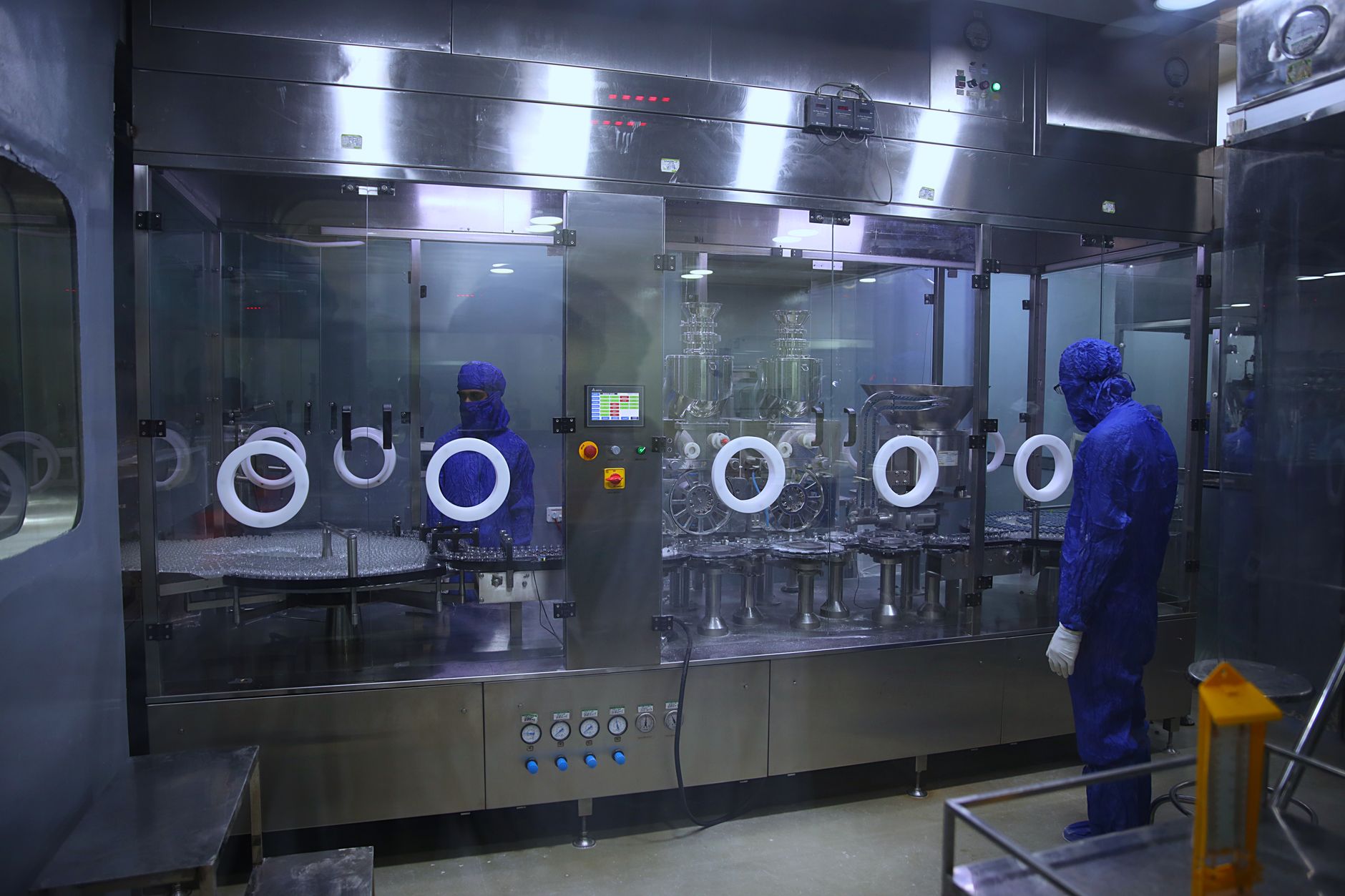 exterior view of a semiconductor fabrication facility with clean-room infrastructure visible through glass panels, photographed at dusk with industrial lighting