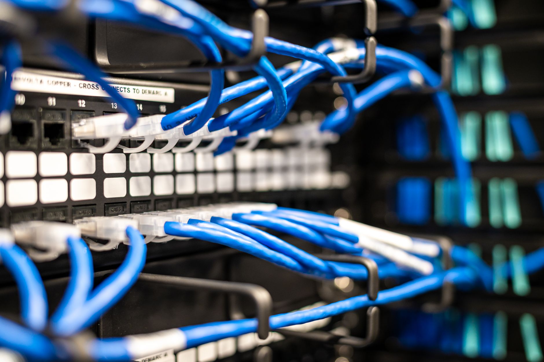rows of server racks inside a large-scale data centre, illuminated by blue and white indicator lights with cable management systems visible along the floor