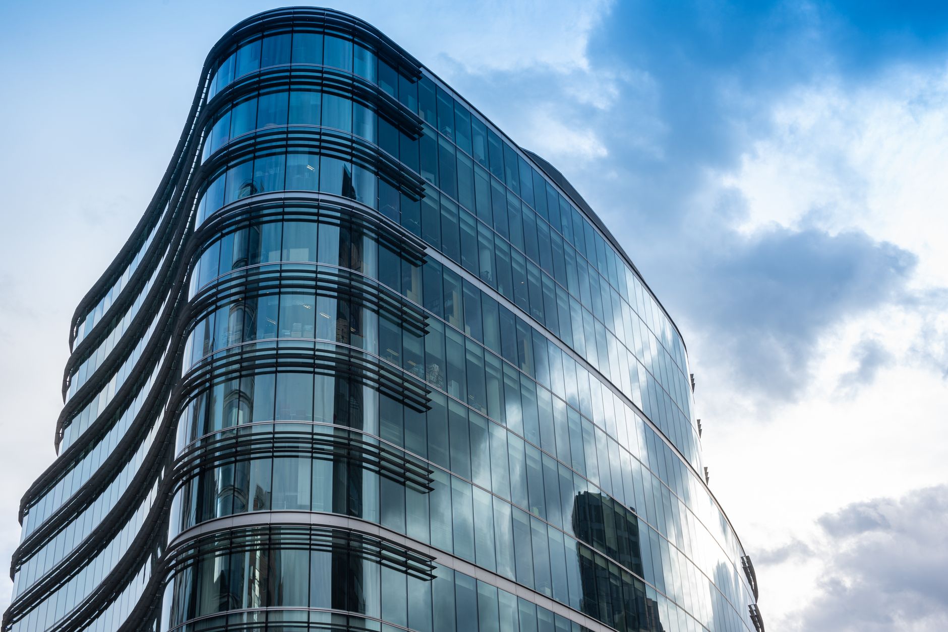 exterior of a glass-fronted commercial office building on a quiet London street, reflecting grey overcast sky