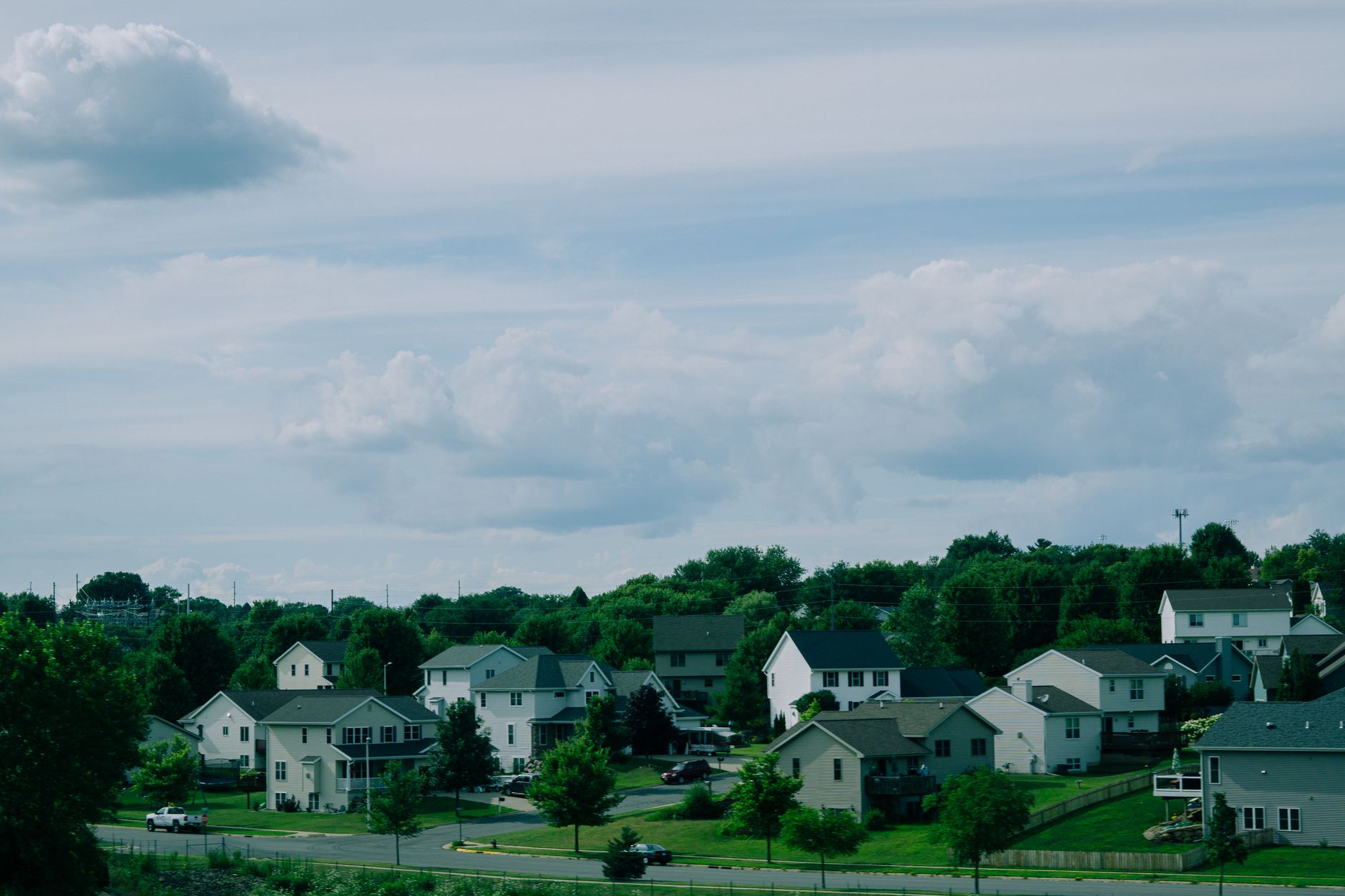 aerial view of a quiet suburban residential neighborhood with rows of single-family homes and empty driveways on an overcast afternoon