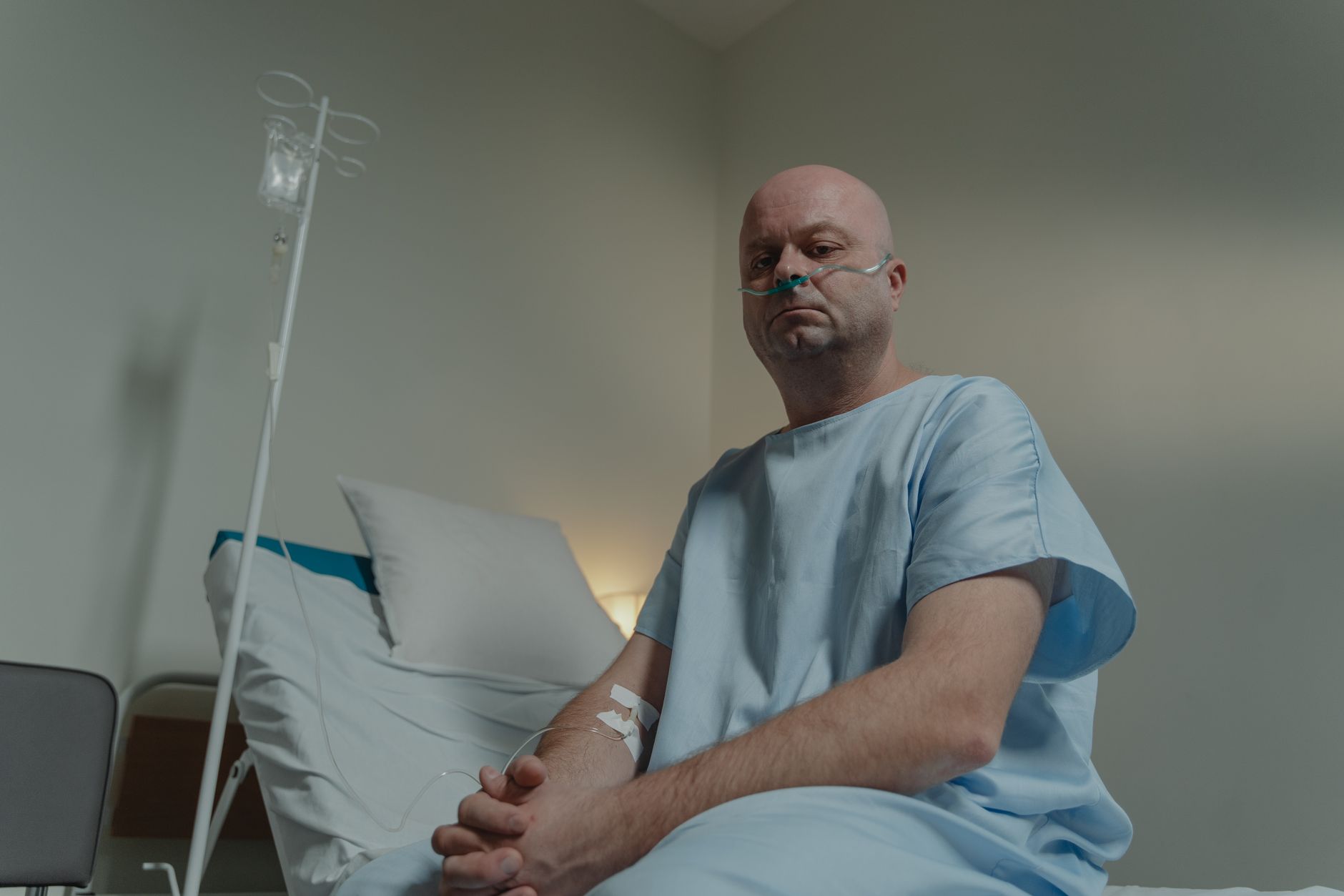 interior of a sparsely equipped oncology ward in a public hospital, with empty IV stands and peeling paint on the walls