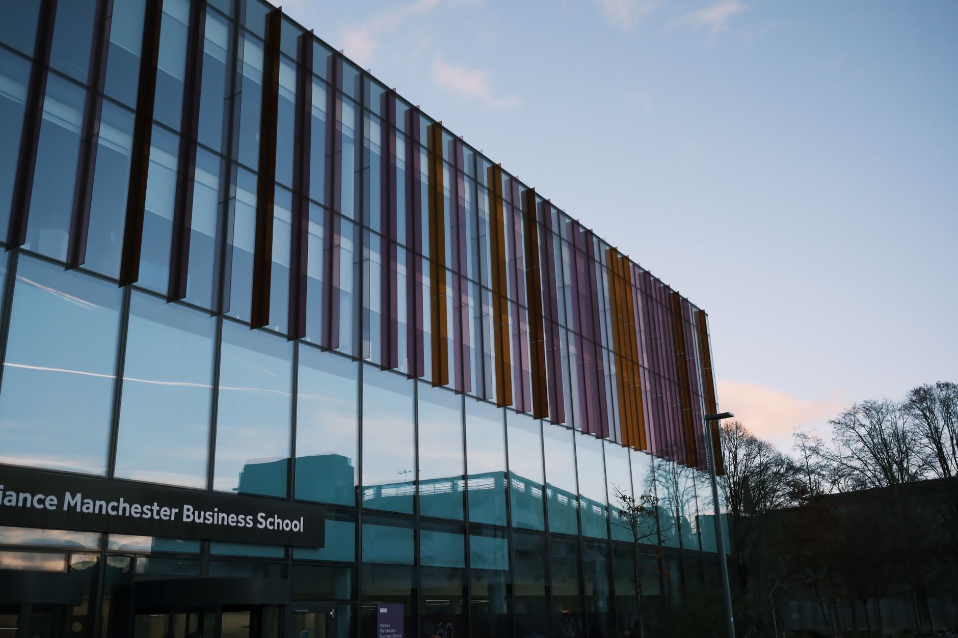 exterior of a modern low-rise tech campus building at dusk with glass facades reflecting a fading sky, surrounded by sparse desert landscaping