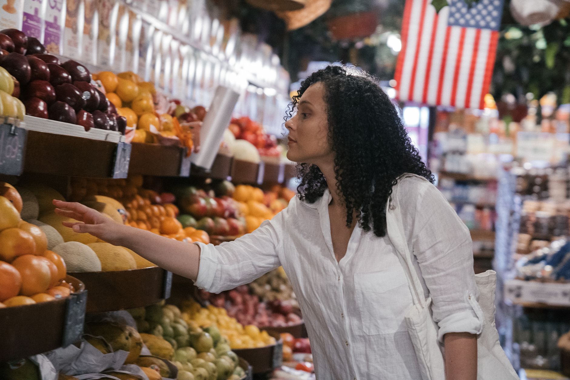wide-angle shot of a well-stocked organic produce section in a grocery store, with rows of labeled vegetables and fruits under warm overhead lighting