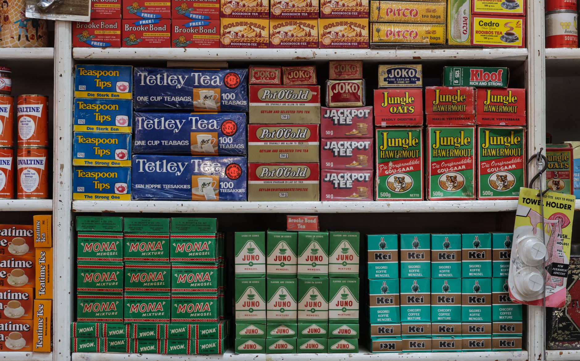 shelf display of store-brand organic packaged goods in a supermarket aisle, price tags visible beneath neatly arranged boxes and cans