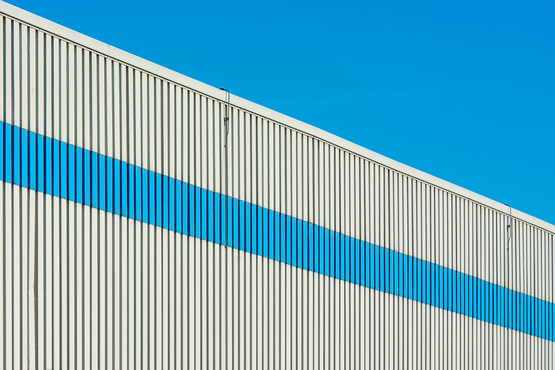 exterior of a large modern healthcare data center facility with server cooling units visible along the building's side, set against a cloudy late-afternoon sky