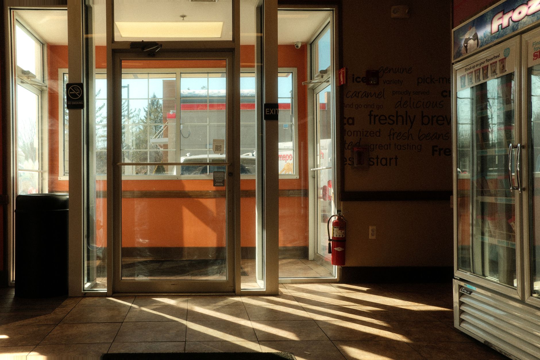 interior of a partially emptied retail store with shelving units stripped bare and fluorescent lighting casting harsh shadows across a tiled floor