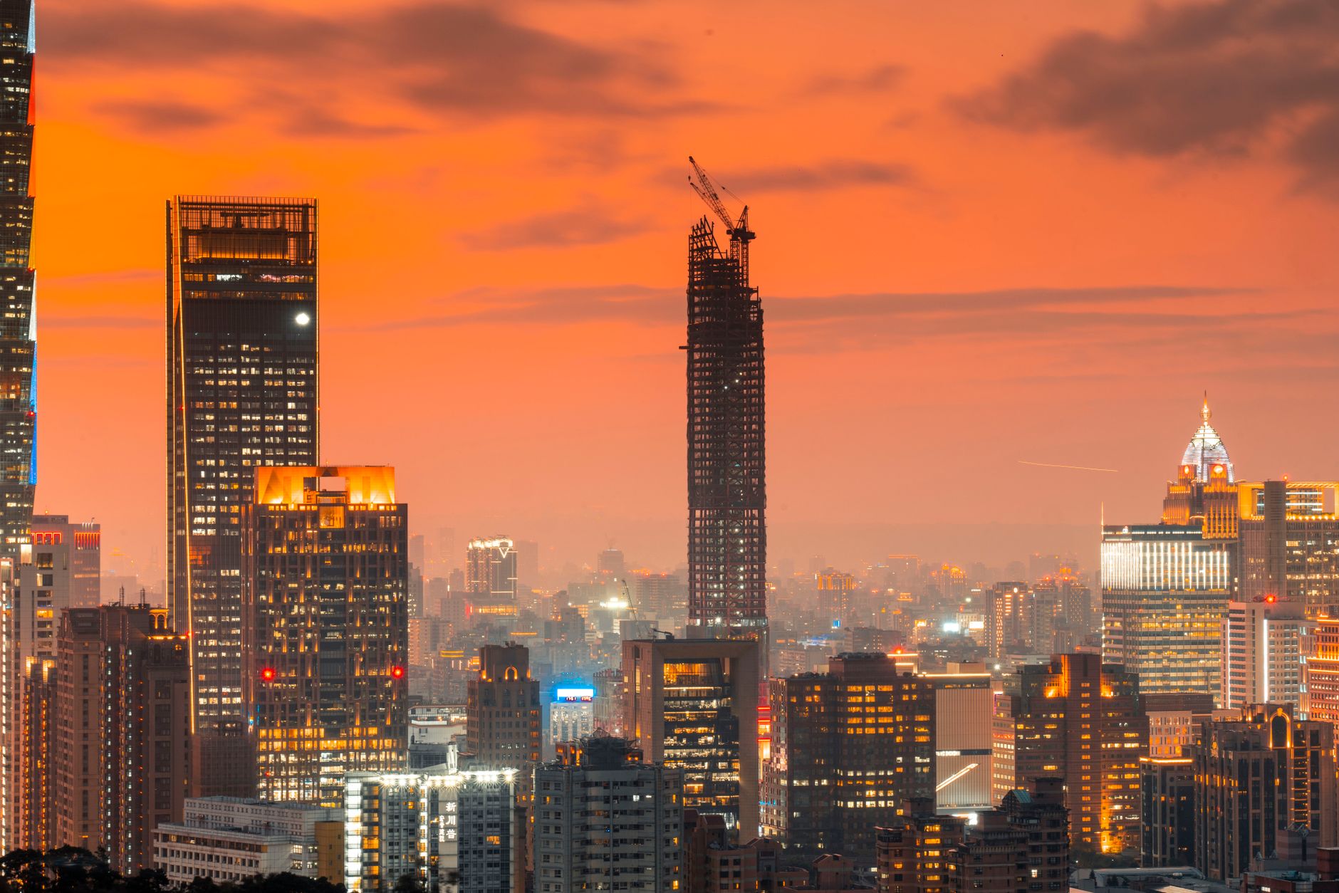 aerial view of the Riyadh skyline at dusk showing construction cranes and glass towers under development against a fading orange sky
