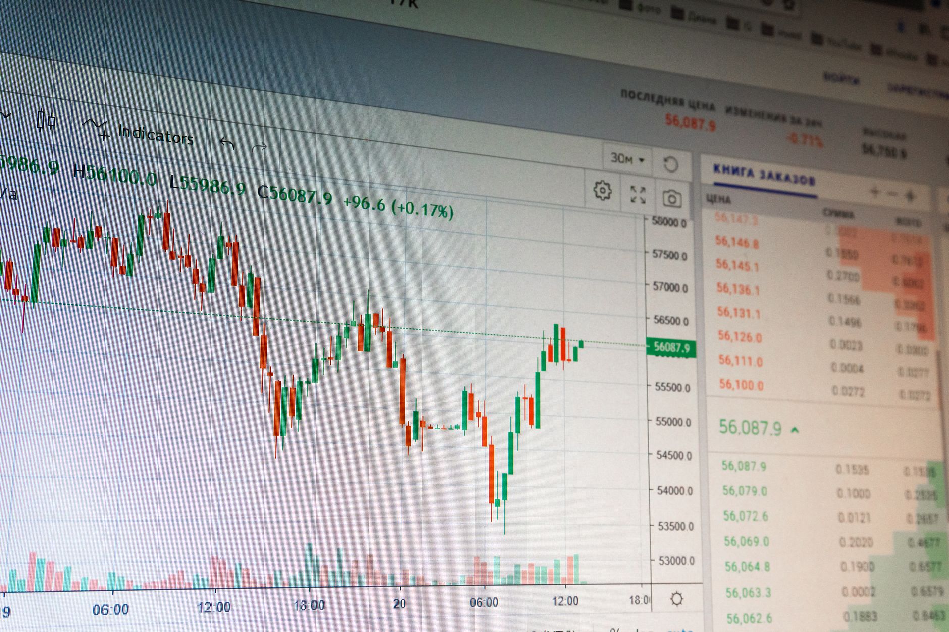 rows of trading terminal screens displaying red percentage indicators and financial ticker data in a dimly lit exchange environment