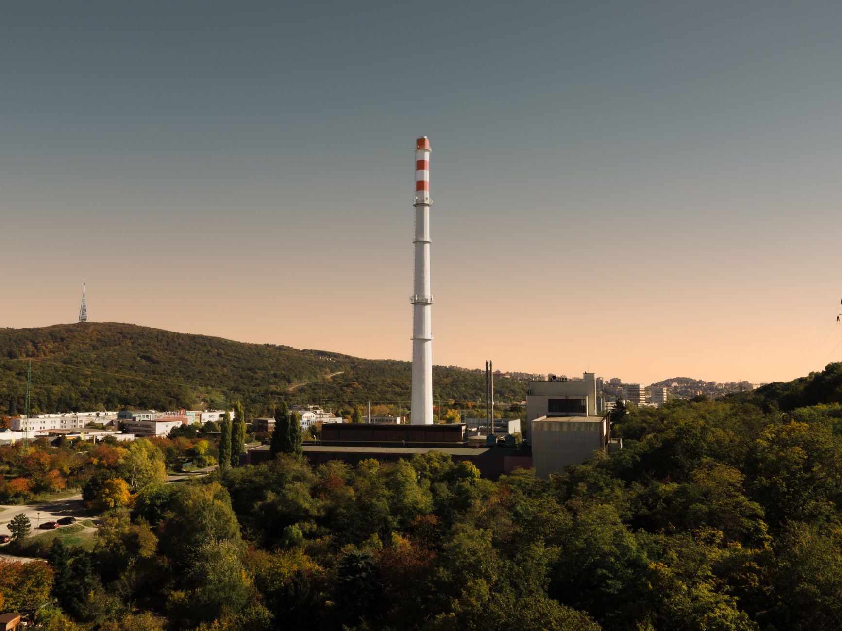 exterior of a large semiconductor fabrication plant in South Korea at dusk, with illuminated signage and industrial chimneys visible against an orange sky