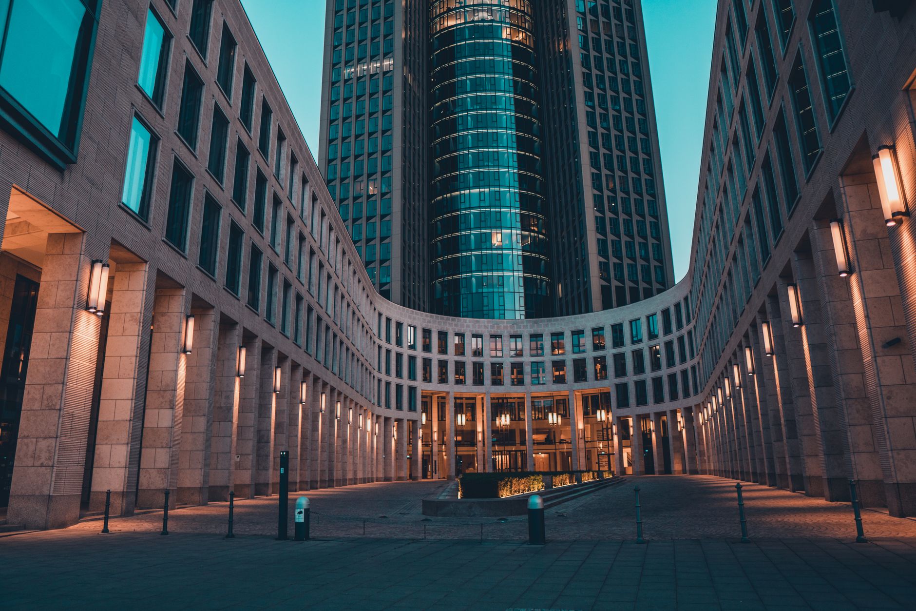 exterior view of a modern financial exchange building at dusk with illuminated facade and empty plaza in foreground