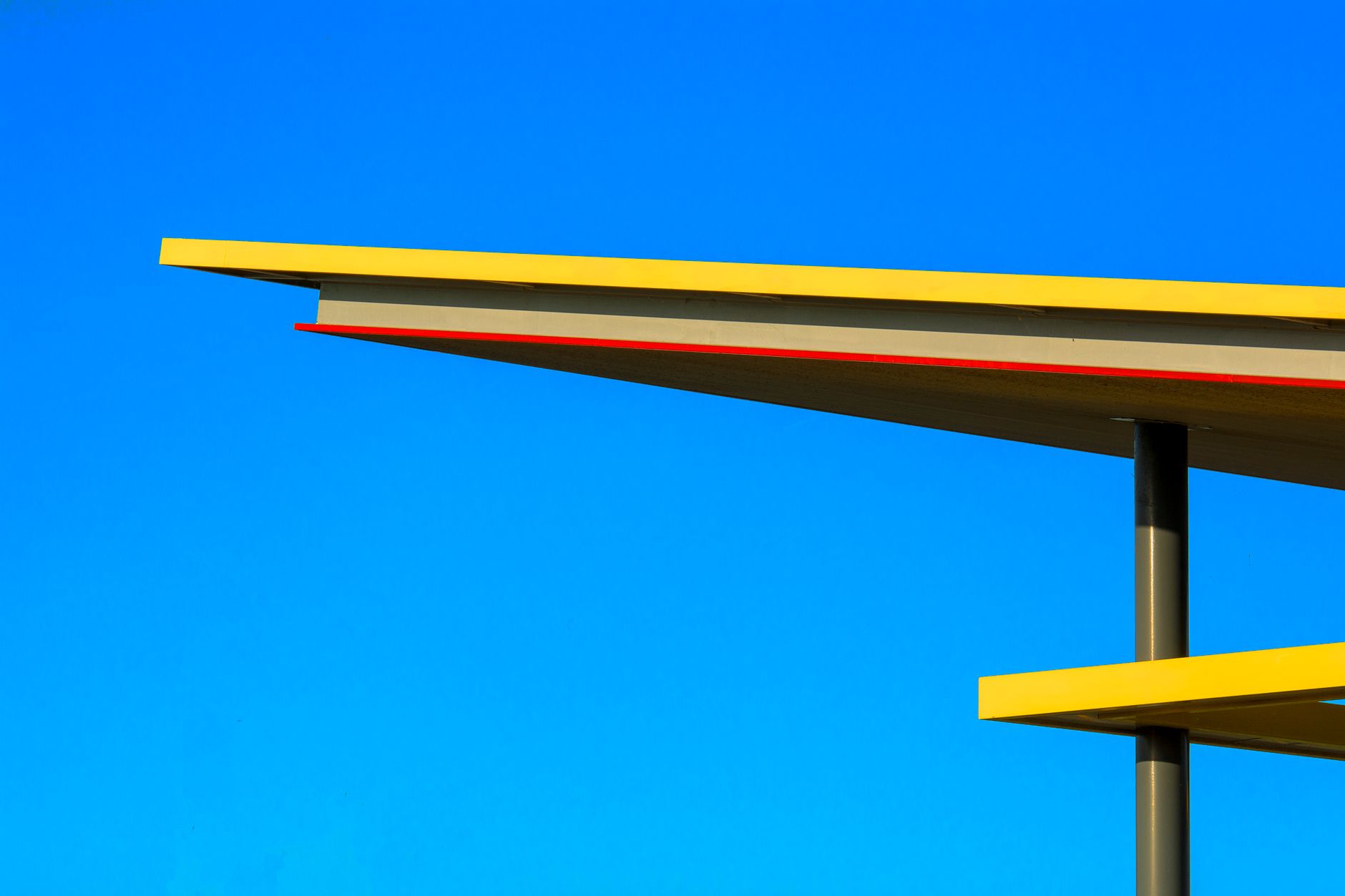 close-up of a gas station price sign displaying fuel costs above four dollars per gallon, set against a clear blue sky in a suburban American streetscape