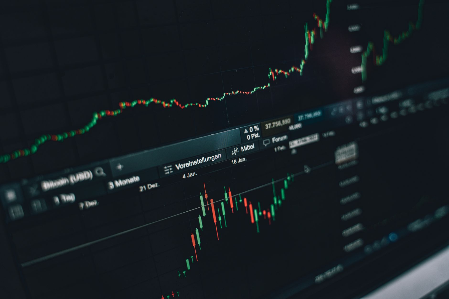 wide-angle view of a financial trading floor with rows of dark monitors displaying cascading price charts in muted red and green tones, no people in foreground