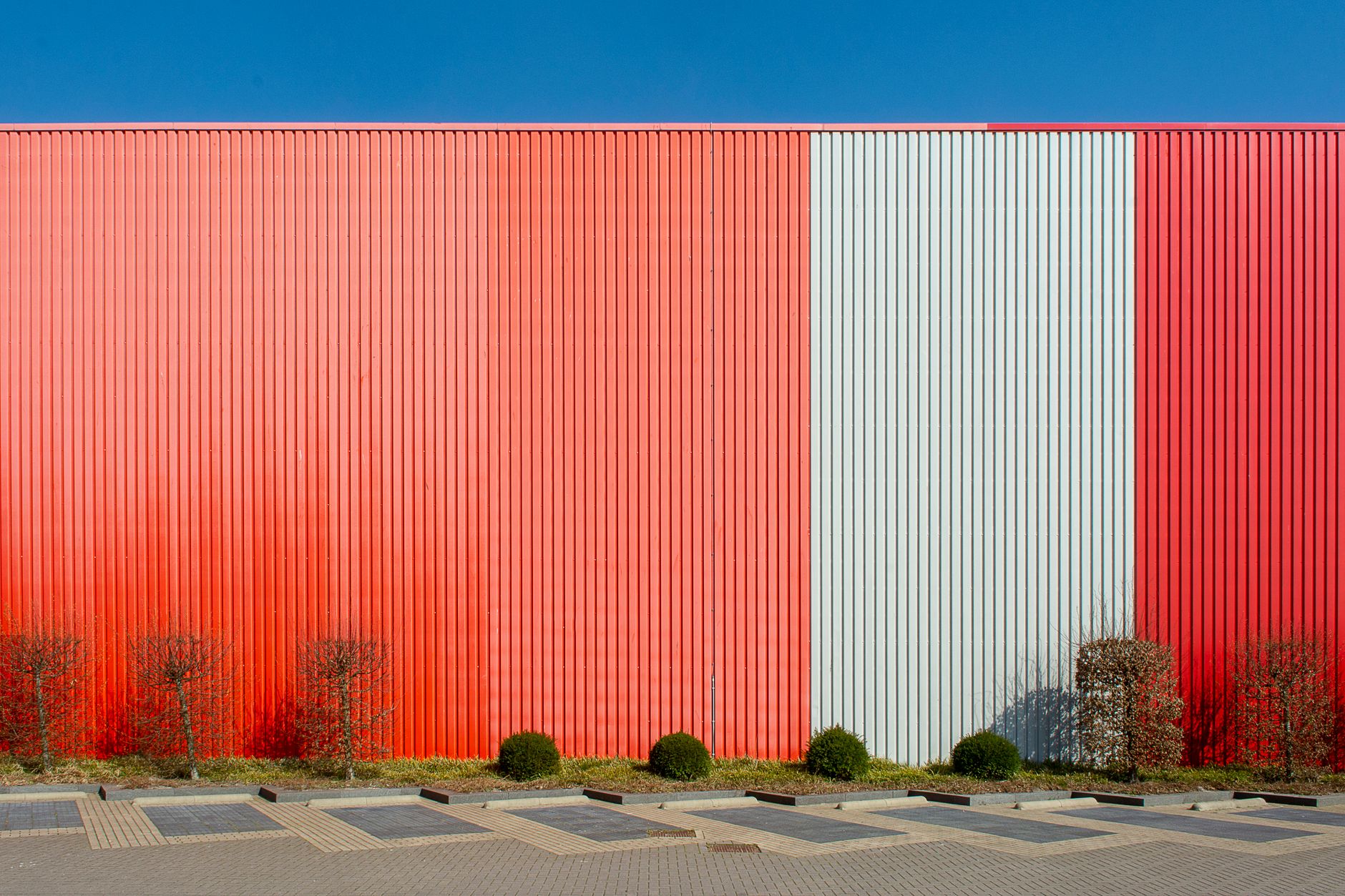 exterior of a large idle automotive assembly plant surrounded by an empty parking lot on an overcast morning