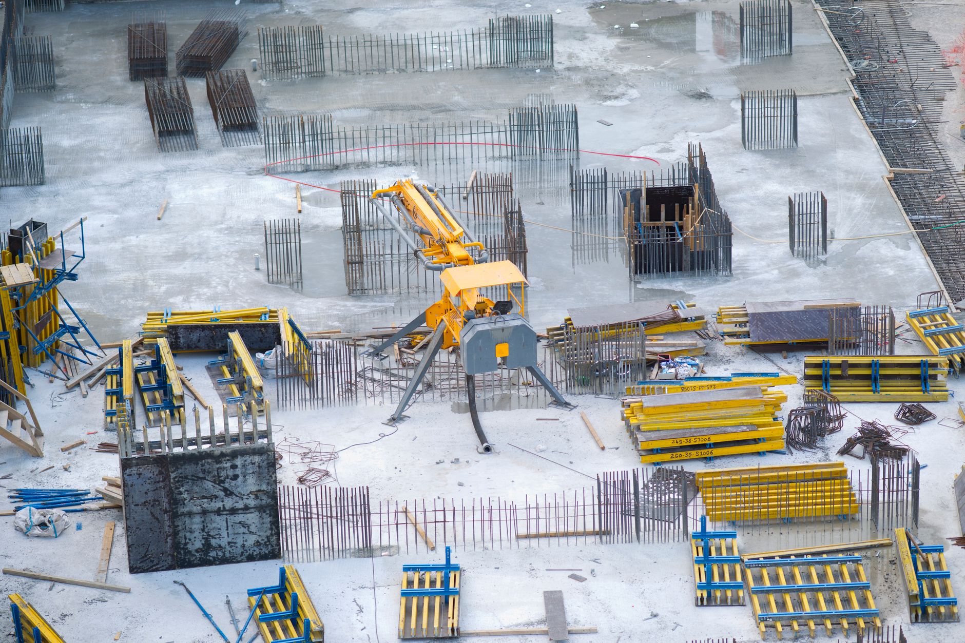 A dusty construction site in an arid Middle Eastern city, heavy machinery idle and surrounded by incomplete concrete foundations under a hazy midday sky
