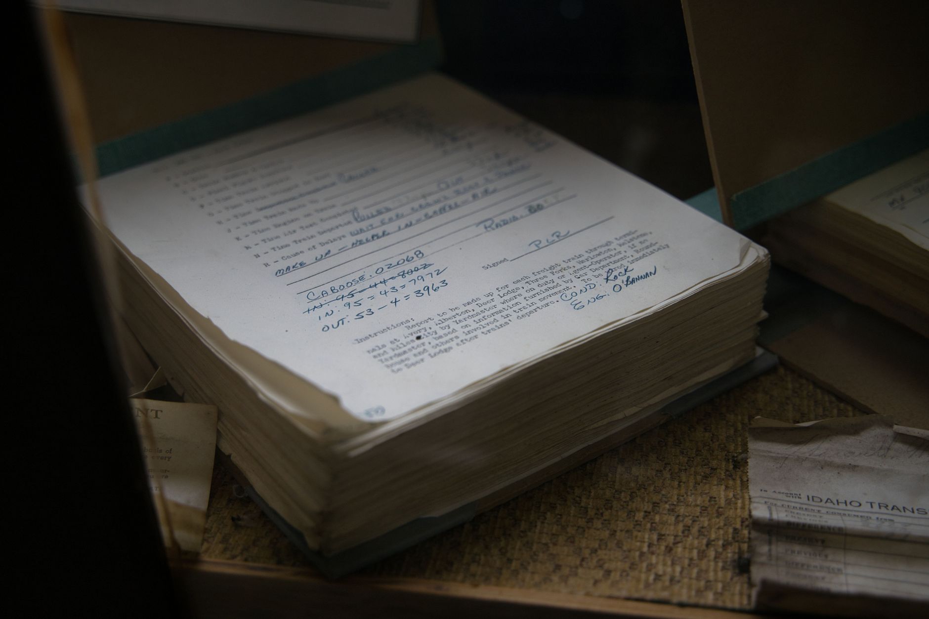 aged leather-bound ledgers and handwritten account books stacked on a wooden desk in a dimly lit archive room