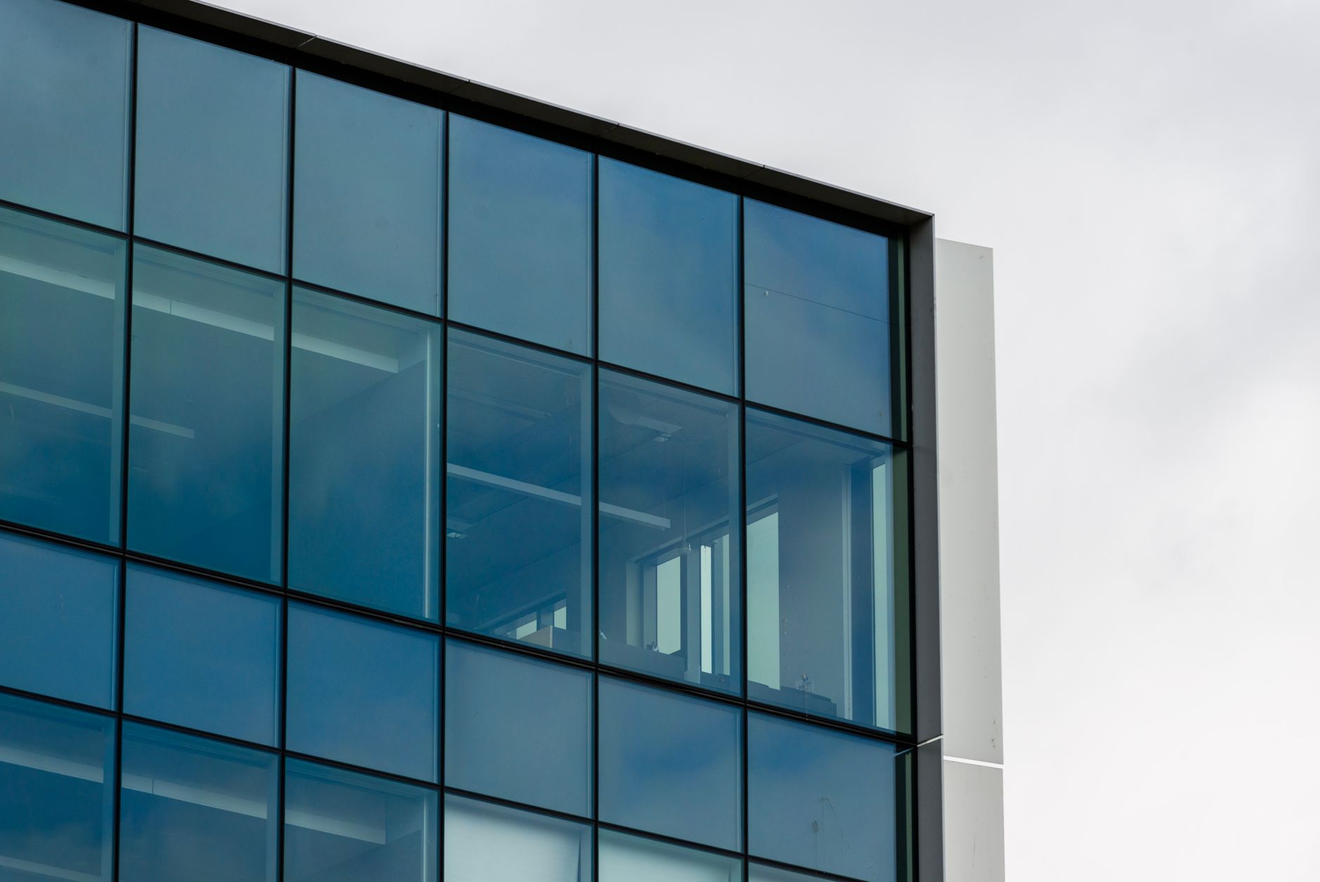 exterior of a sleek corporate office building in San Francisco's Mission District at dusk, with floor-to-ceiling glass windows reflecting the fading sky