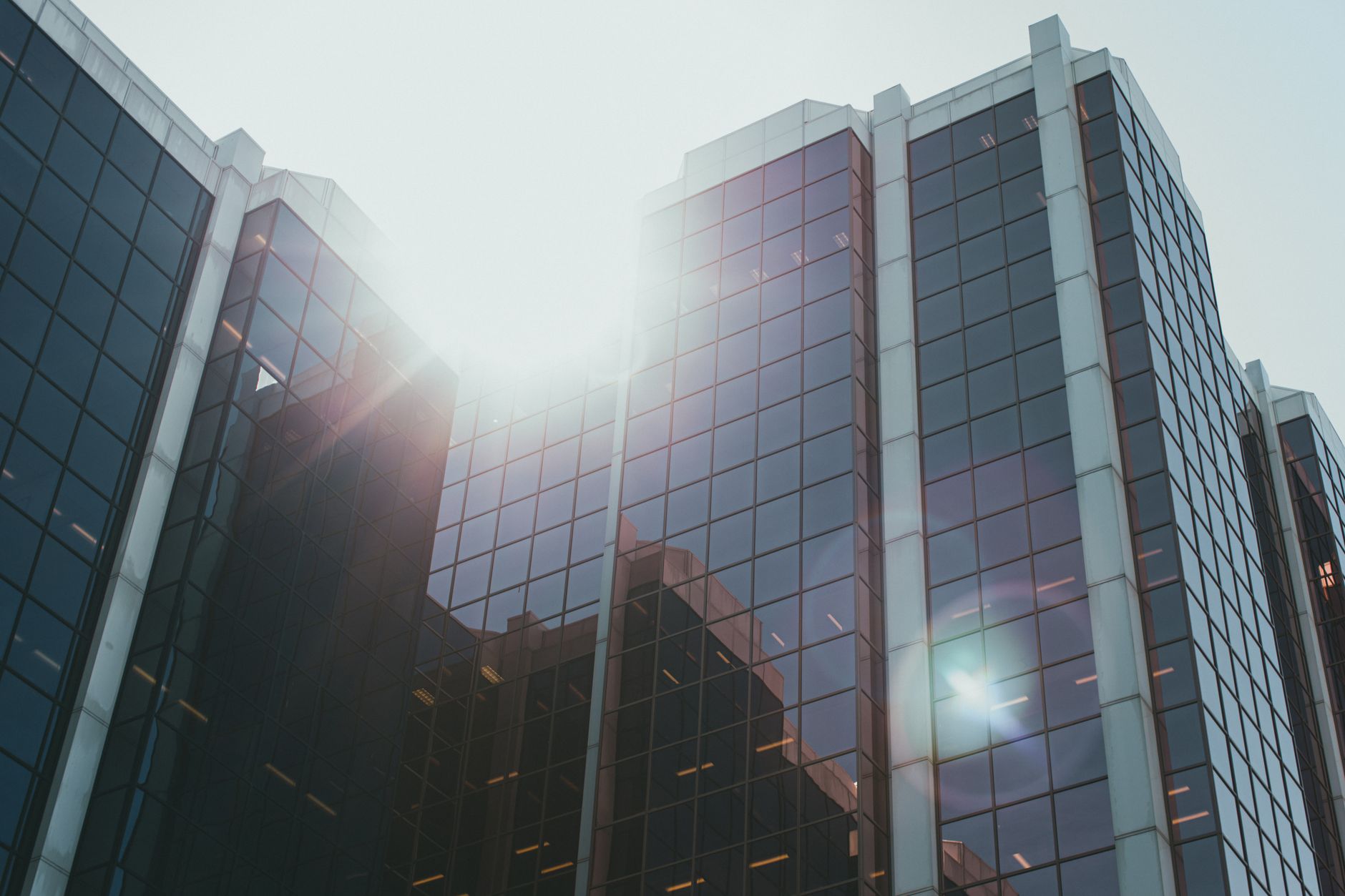 exterior view of a modern tech office building in Tel Aviv at midday, glass facade reflecting the skyline