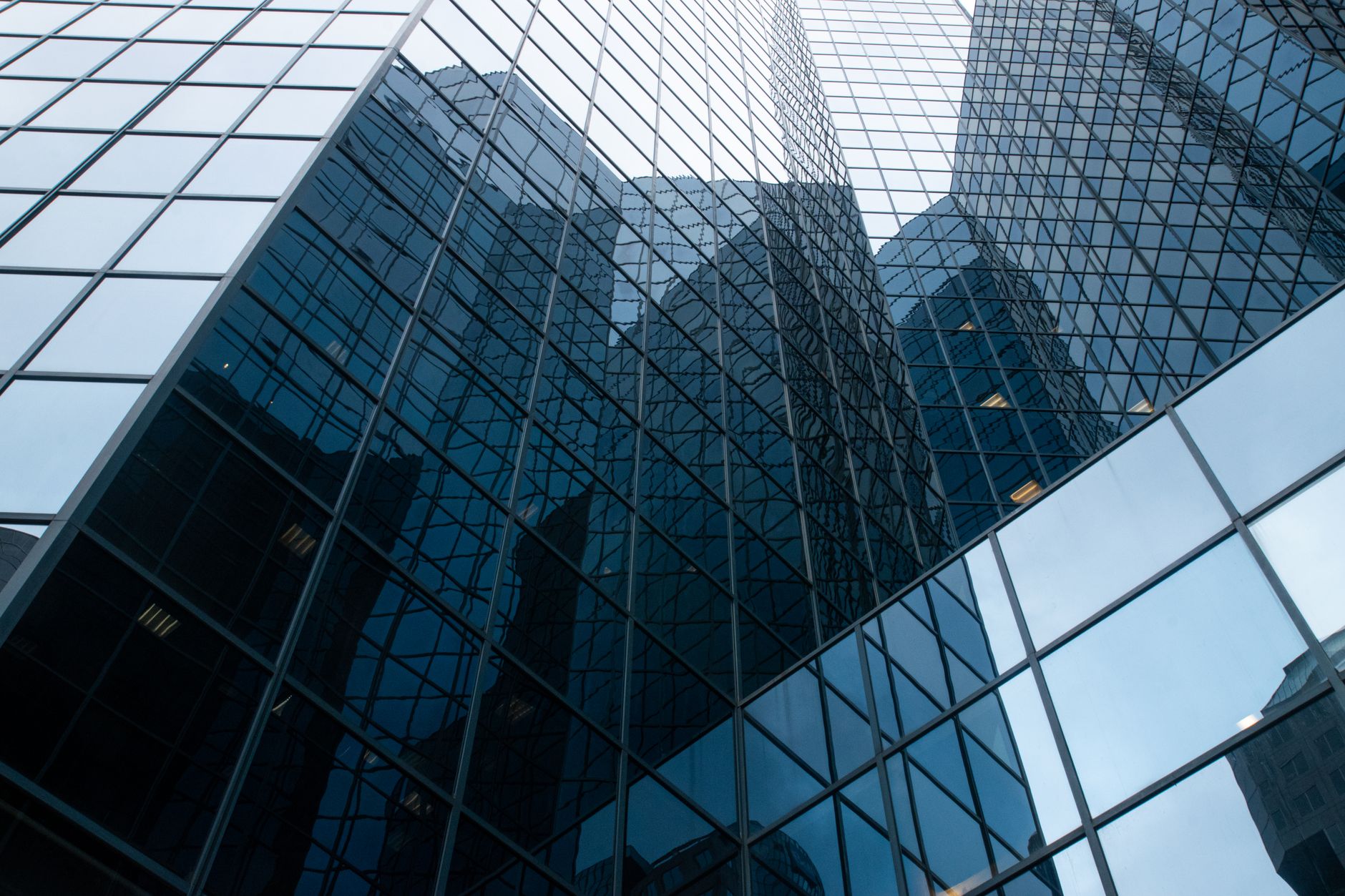 exterior of a large financial district office tower at midday with quiet streets below and minimal foot traffic, reflecting a slow mid-summer business environment