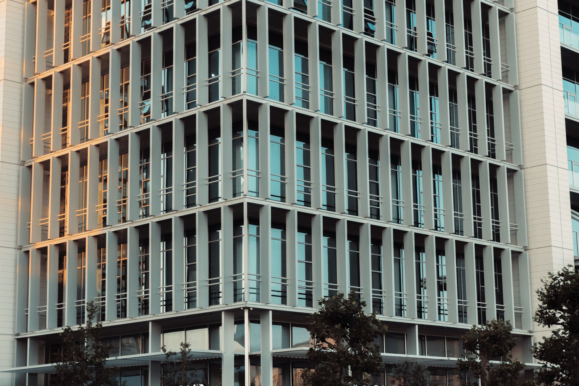 exterior of a modern commercial office building in Tel Aviv at dusk, glass facade reflecting the city skyline