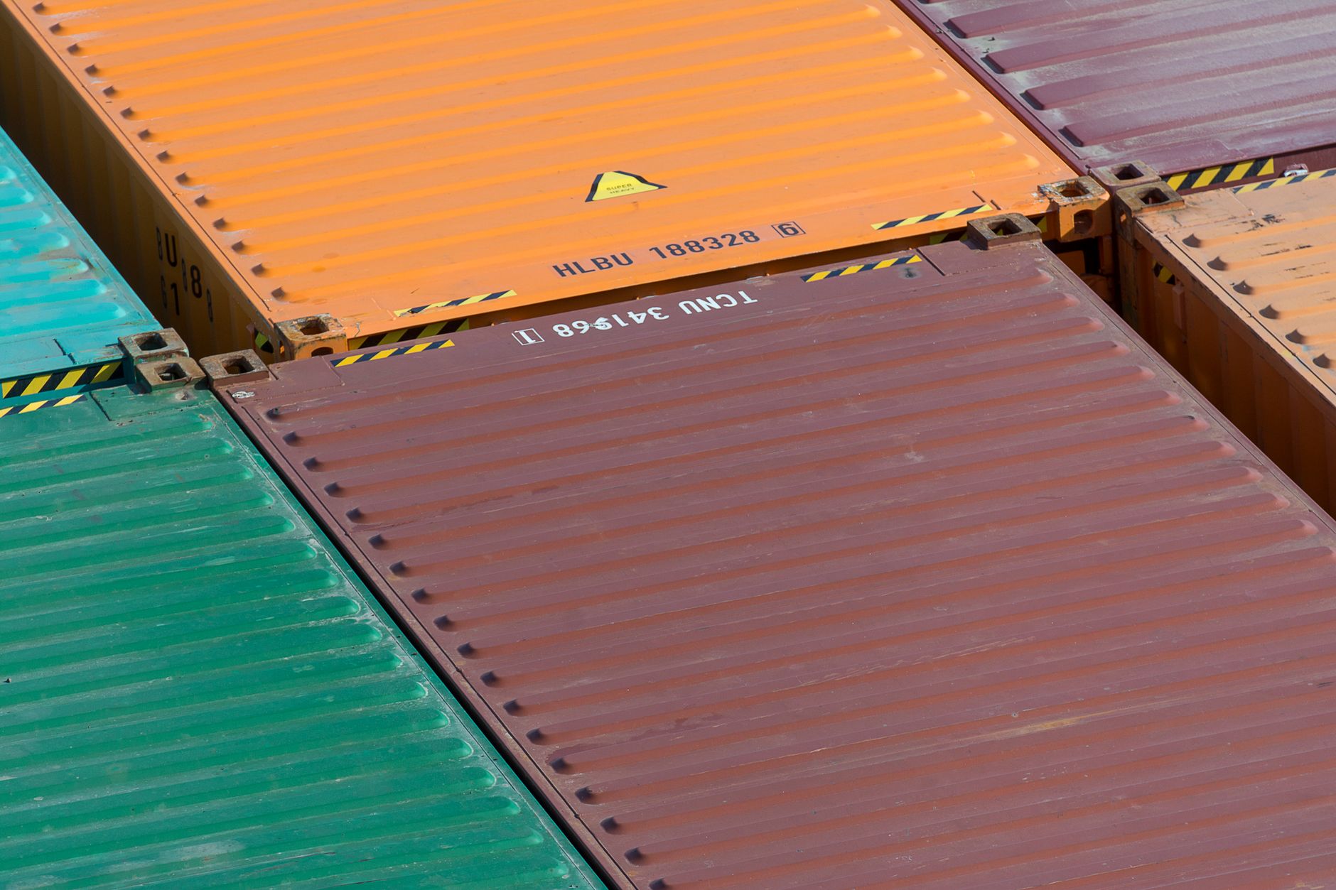 aerial view of a busy cargo container terminal on the Canada-U.S. border with rows of shipping containers and freight trucks queued at inspection lanes