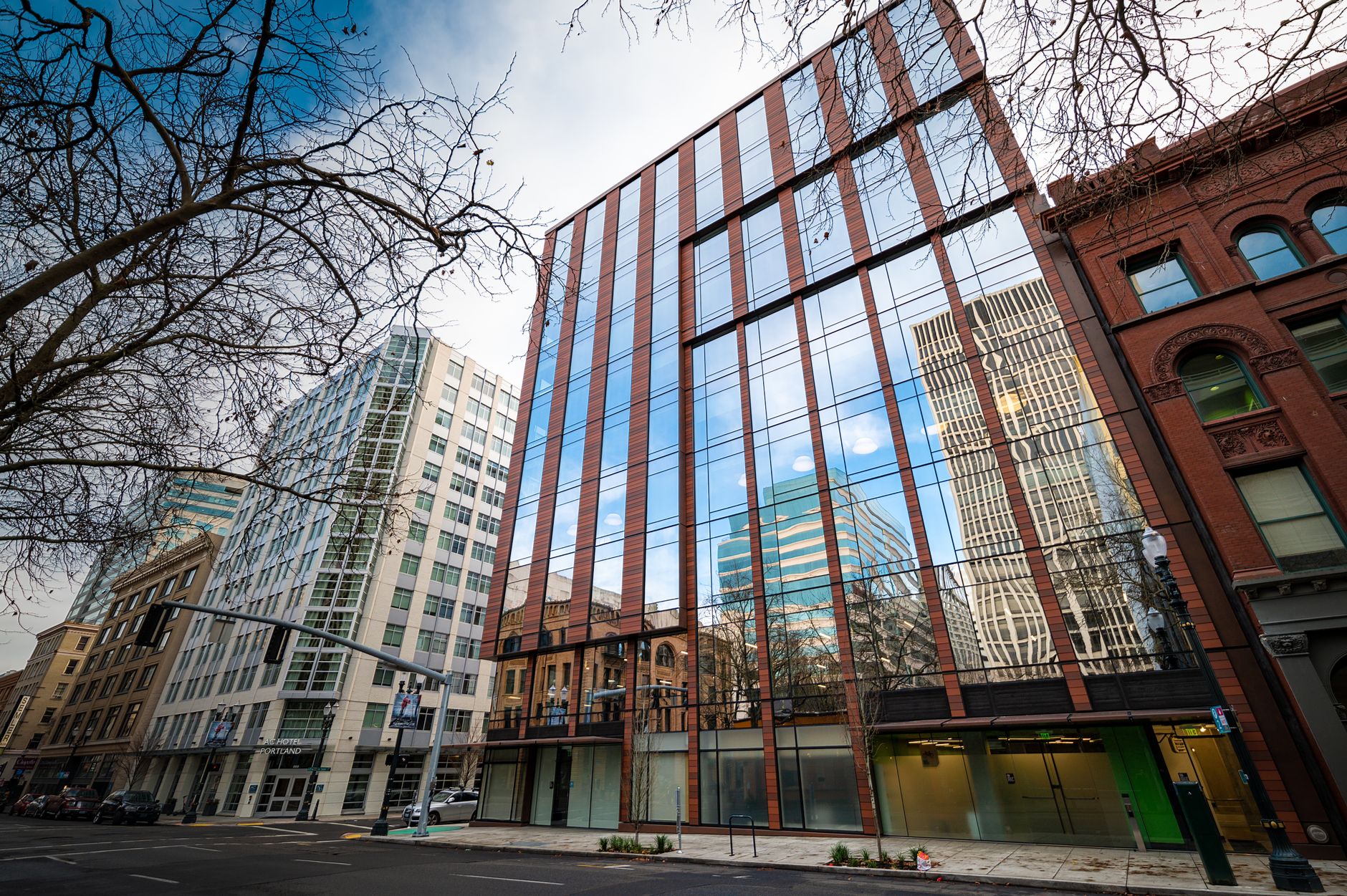 exterior view of a modern financial technology office building at dusk, glass facade reflecting city lights with a wide urban street visible in the foreground