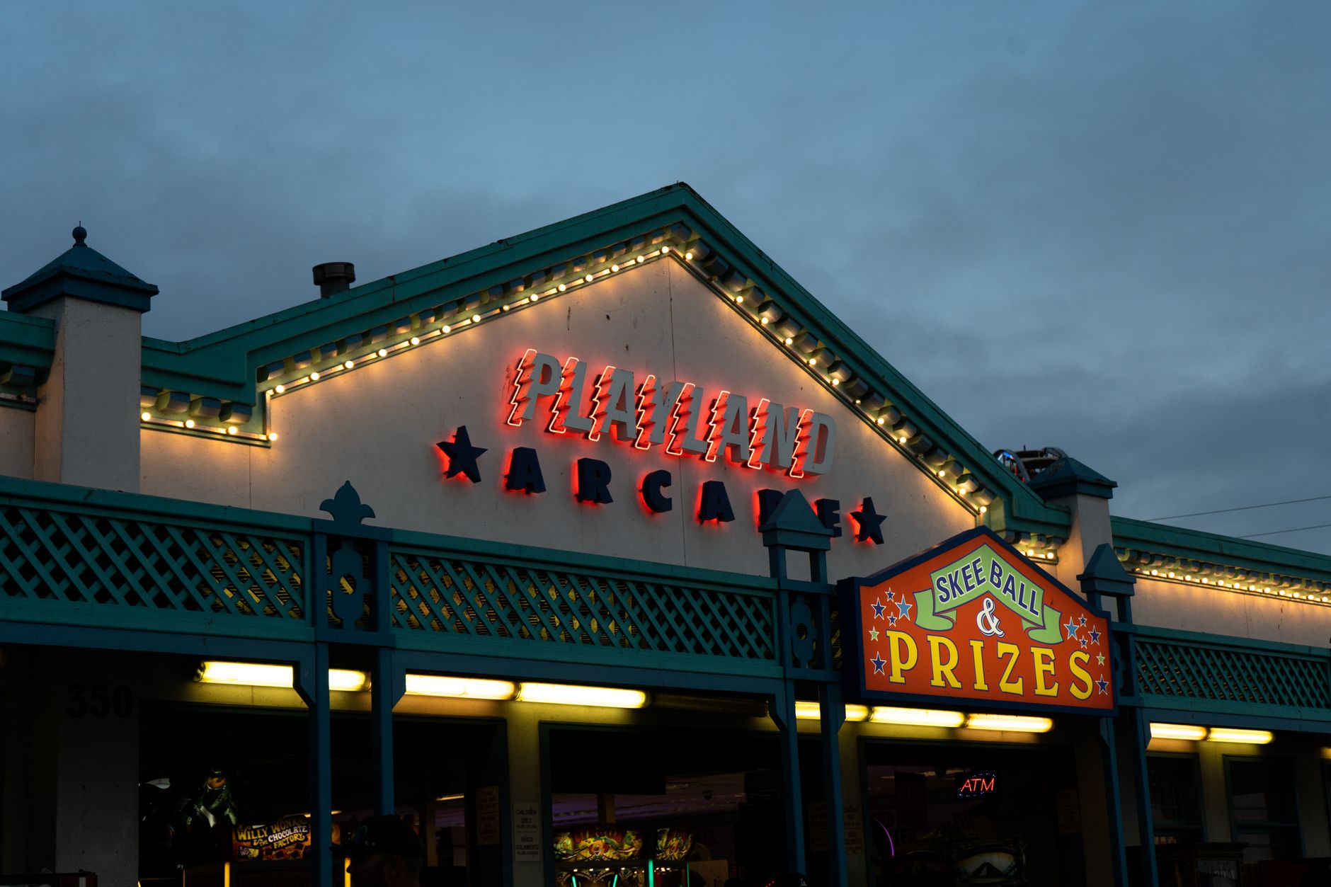 exterior of a midscale highway hotel at dusk, with a well-lit parking lot and interstate signage visible in the background