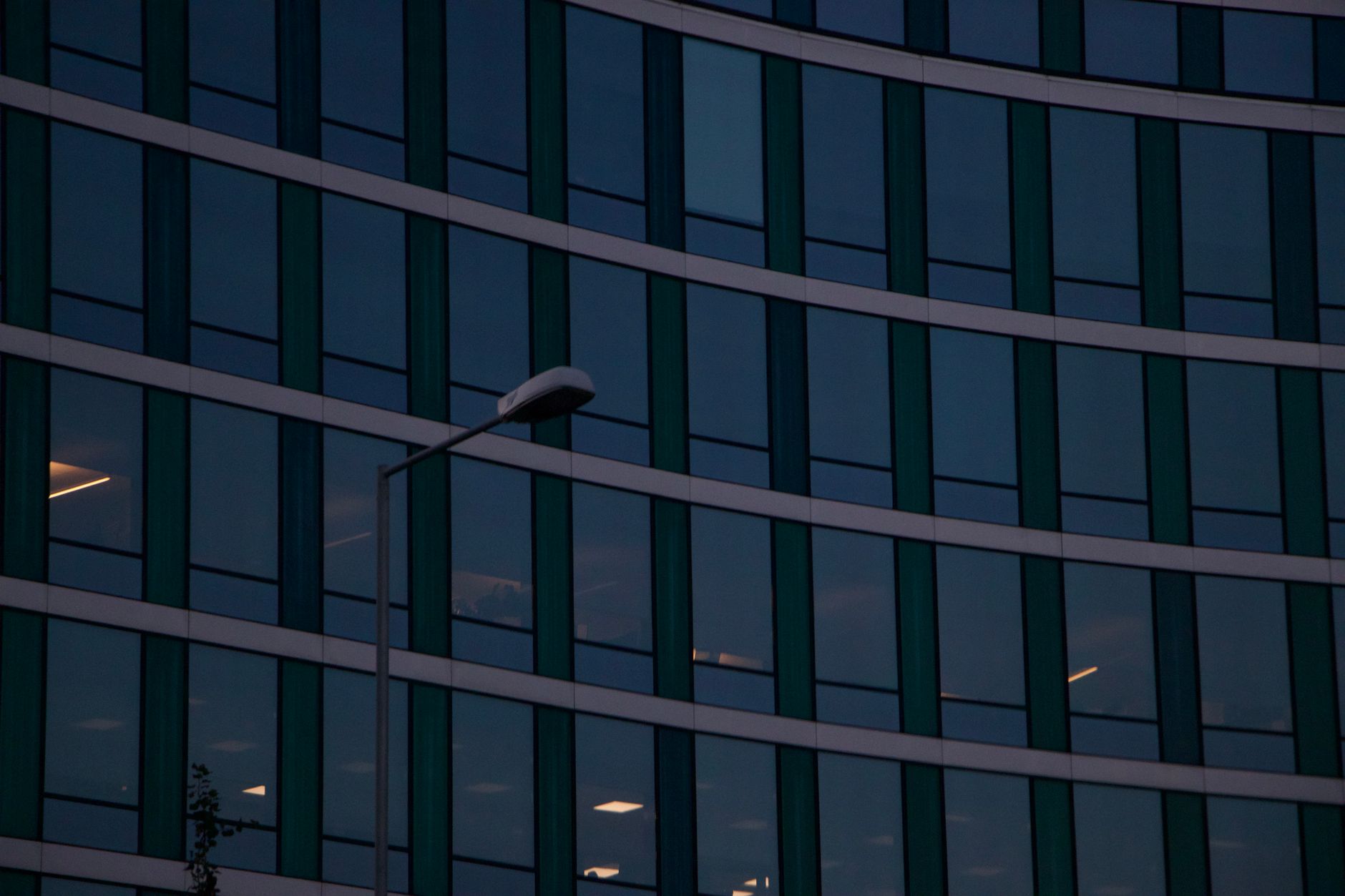 exterior facade of a modern financial exchange building at dusk, glass and steel architecture reflecting amber sky, street-level view with no foot traffic