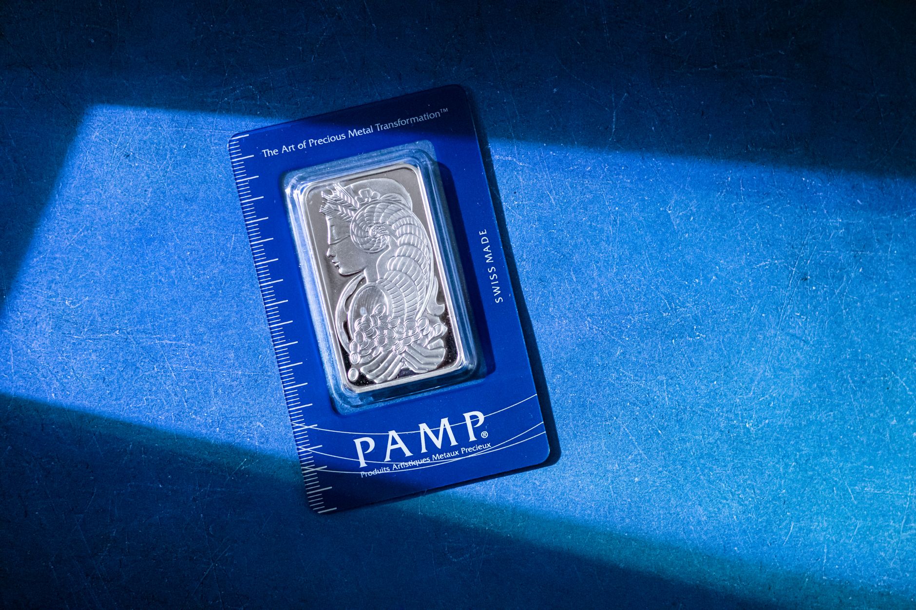 close-up of gold and silver bullion bars stacked on a vault shelf under low industrial lighting