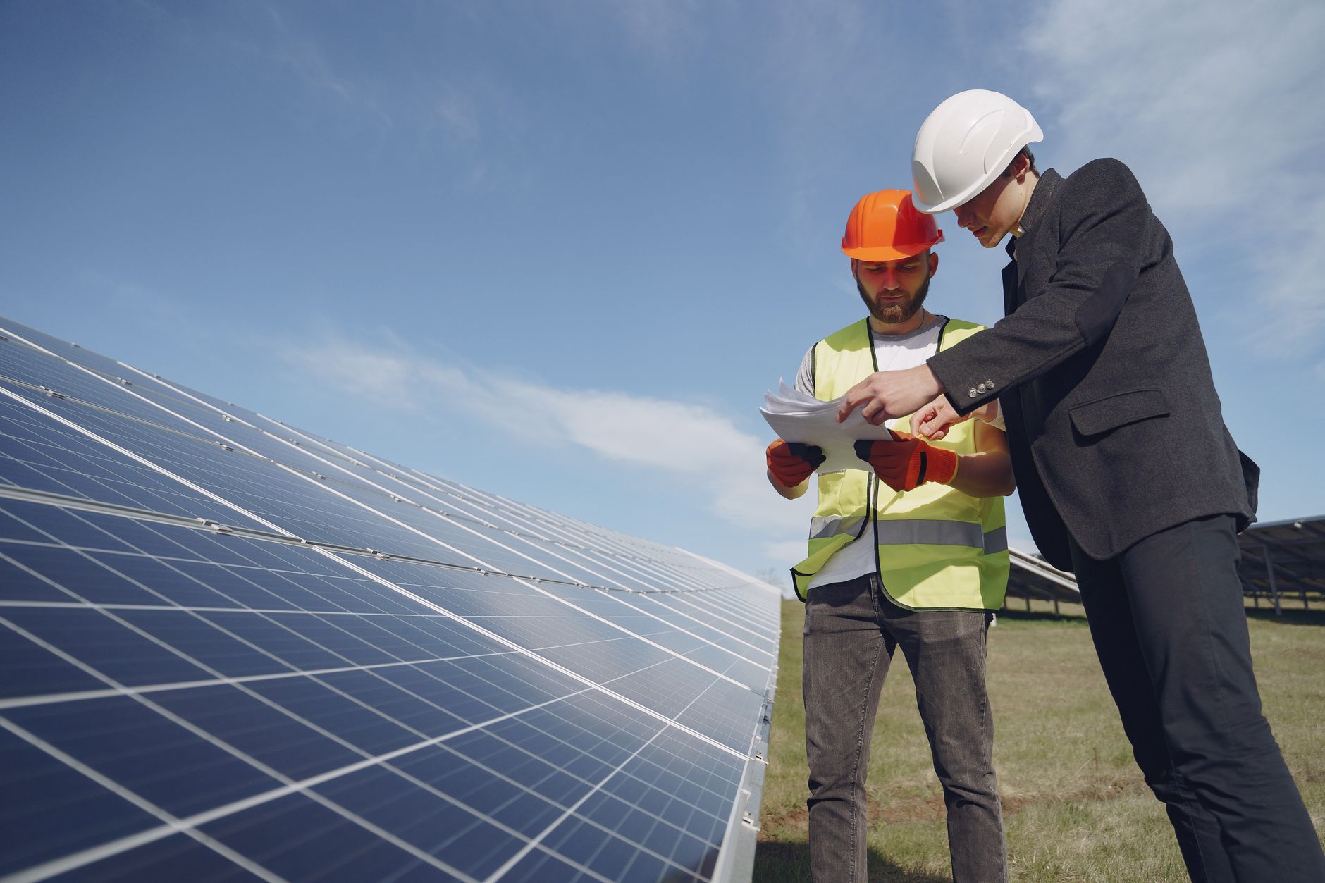 exterior of a solar panel manufacturing facility with rows of panels visible in a large industrial yard at midday