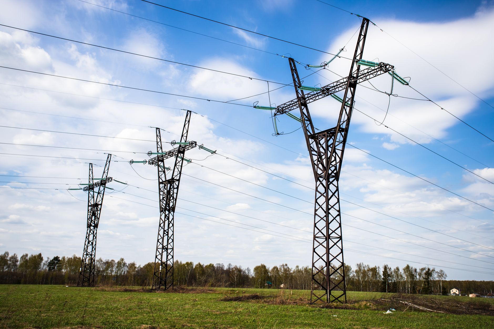 rows of high-voltage power line towers stretching across a suburban landscape in New York's lower Hudson Valley on a clear summer morning