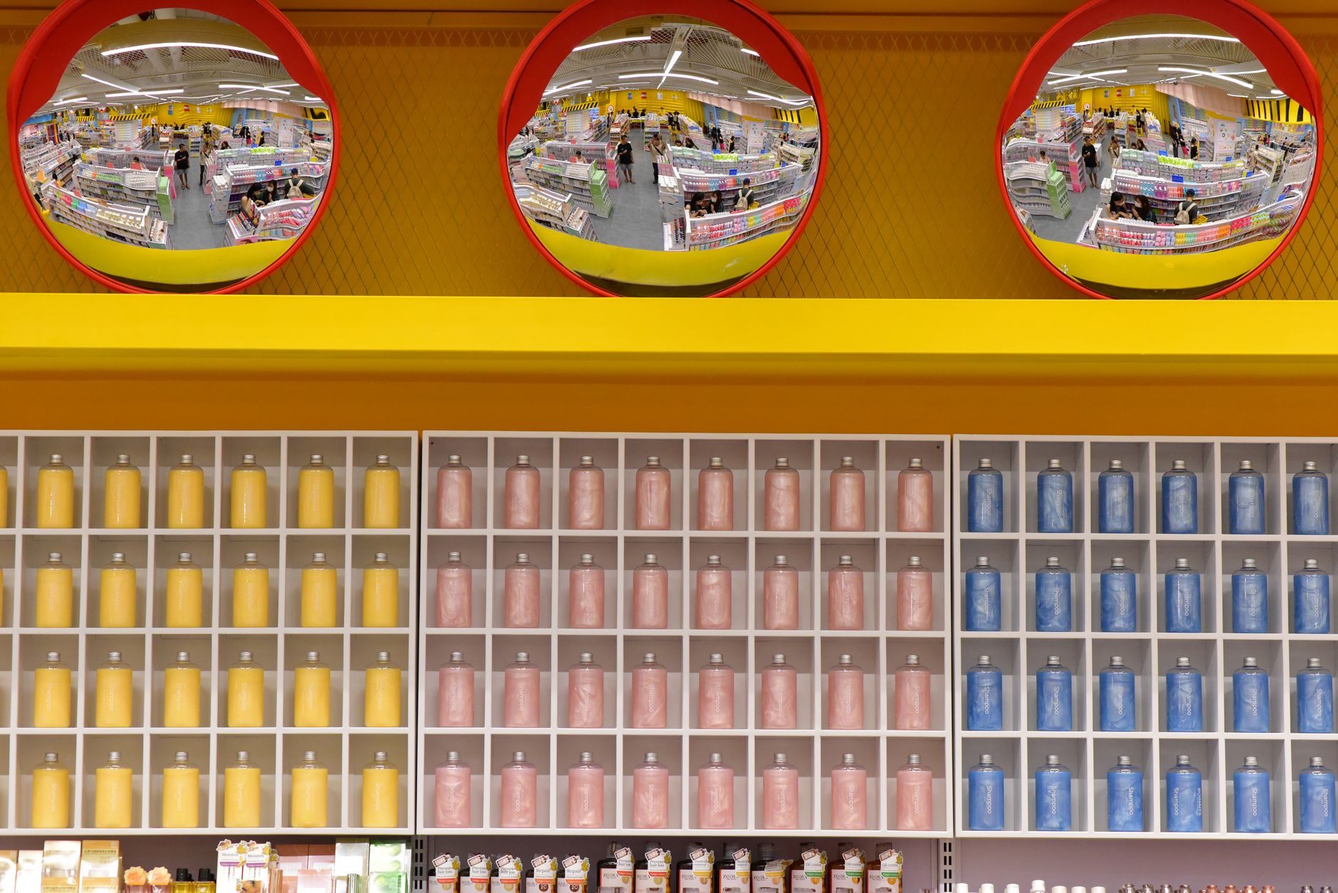 wide interior aisle of a large warehouse retail store showing shelving units stocked with bulk goods and a membership services desk visible in the background
