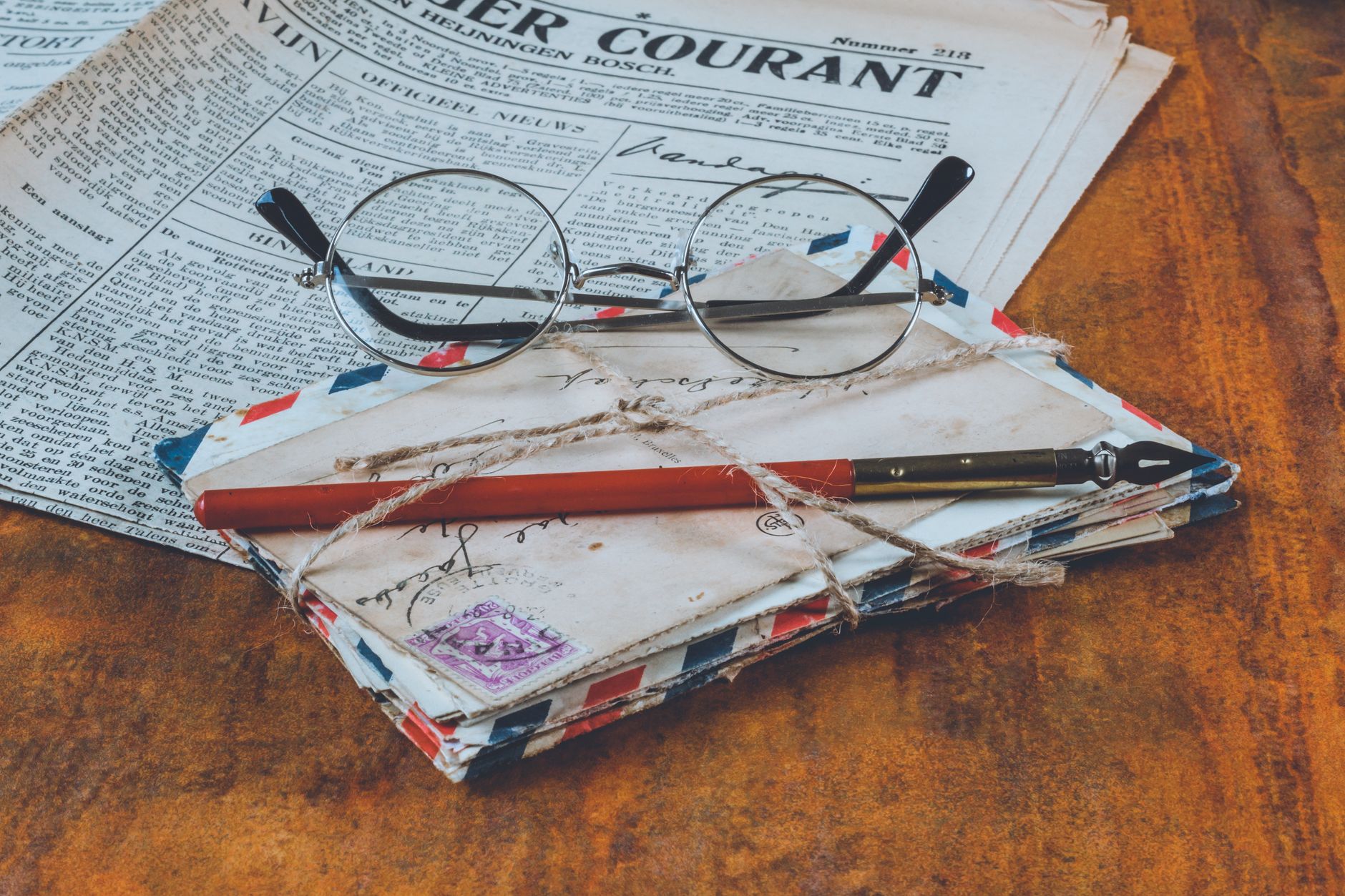 a collection of open insurance brochures and enrollment forms spread across a wooden desk beside a pair of reading glasses and a pen