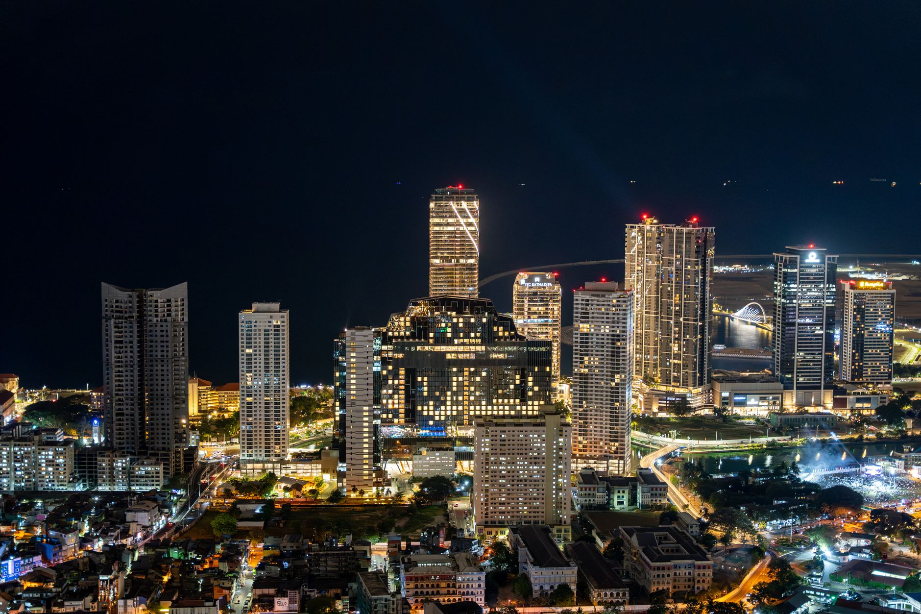 aerial view of the Tel Aviv skyline at dusk with illuminated office towers reflected in the Mediterranean coastline, as seen from a distance