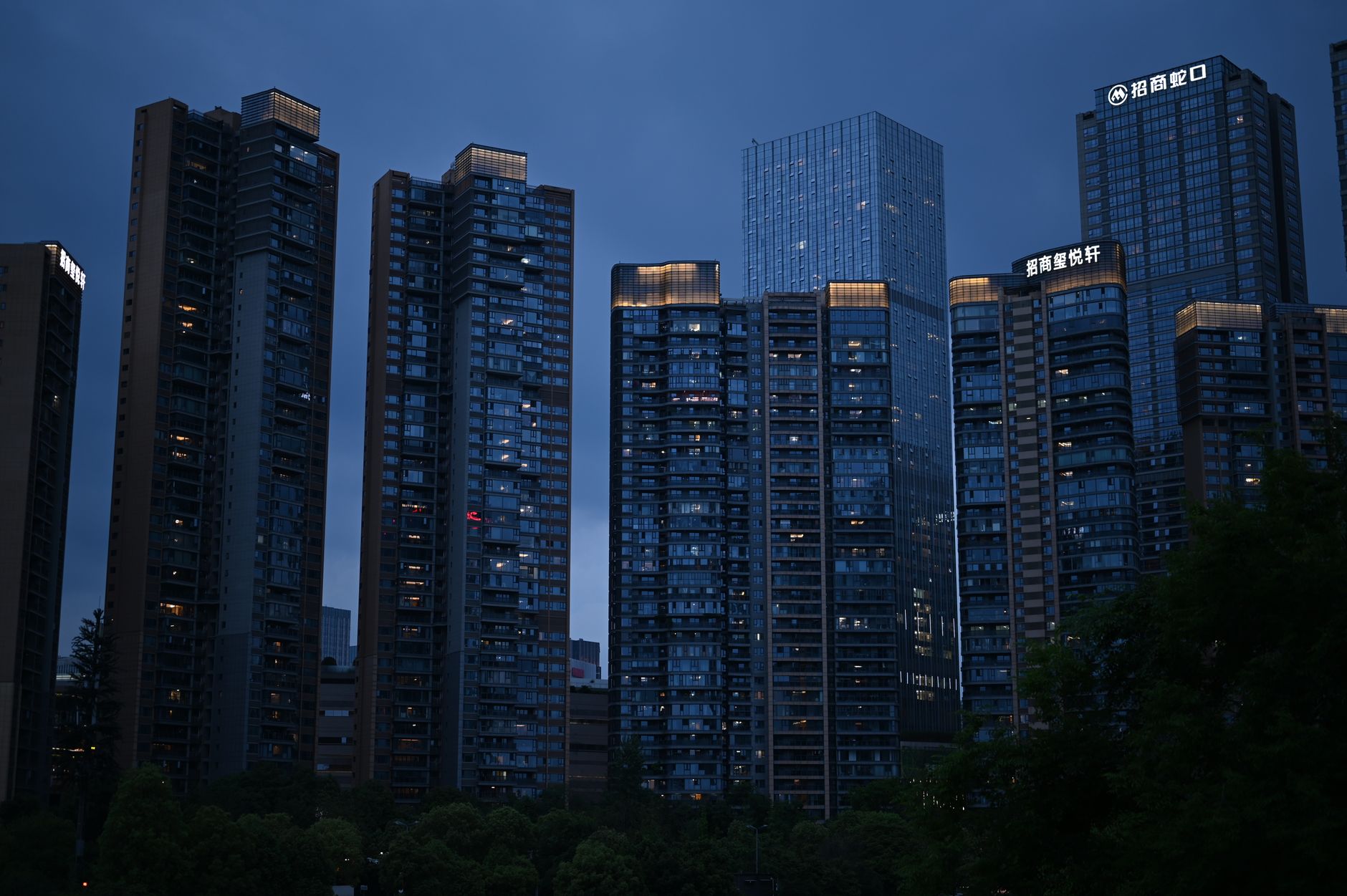 exterior of a financial crime investigation office building at dusk, with illuminated windows and security signage visible near the entrance
