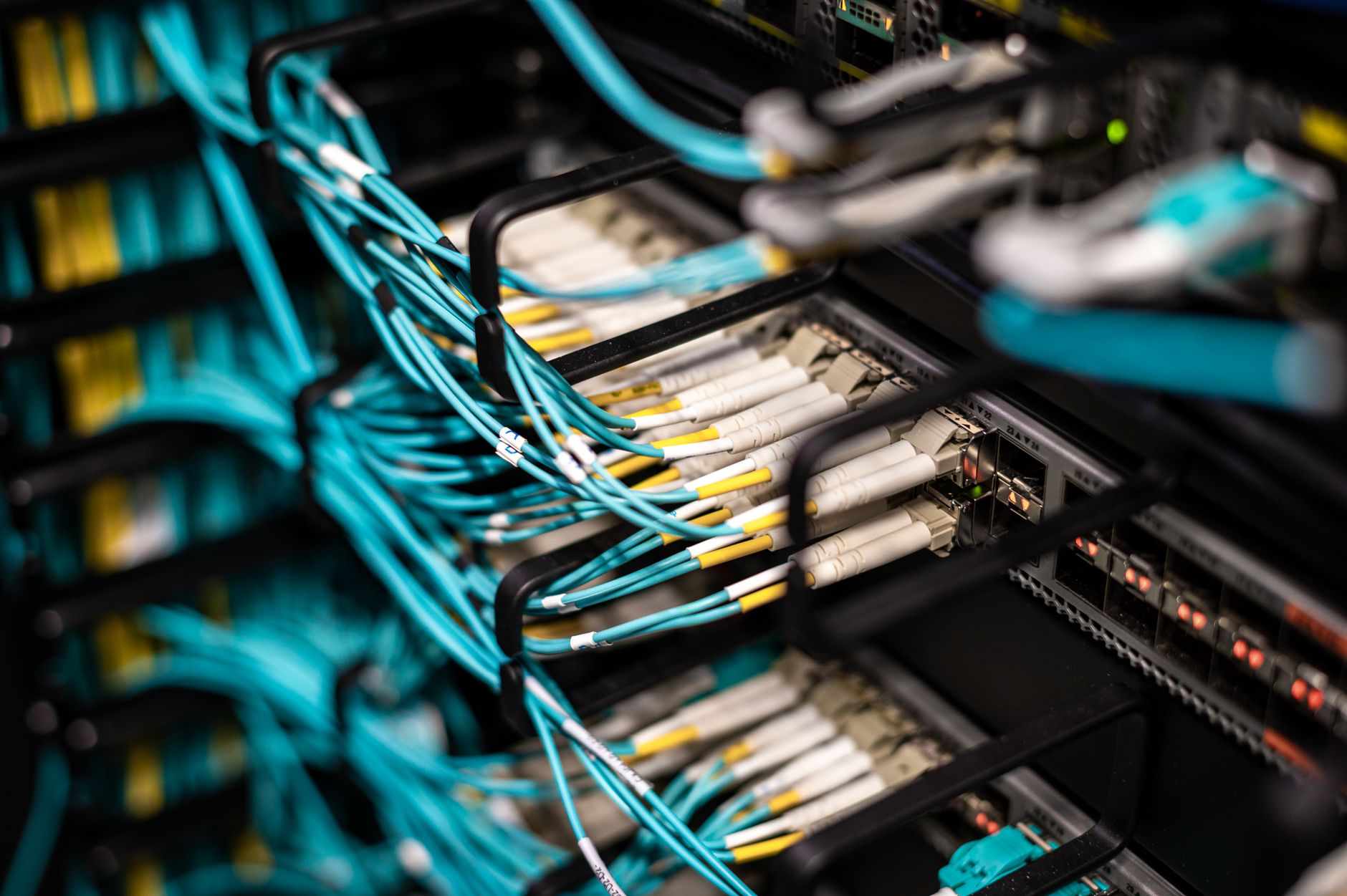 Interior of a data centre housing cryptocurrency mining rigs, with rows of hardware units connected by cables and faint indicator lights visible in a dimly lit room