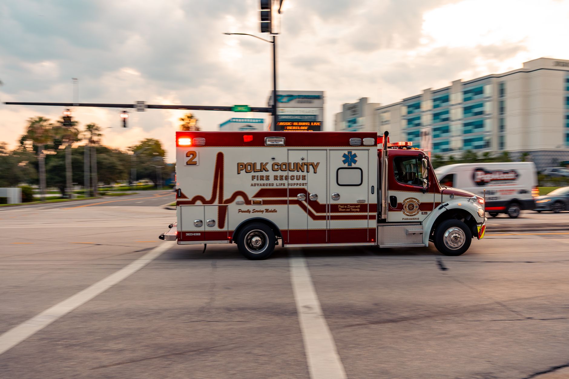 exterior of a modern fire station building at midday with emergency vehicles parked in the bay, set against a clear Florida sky