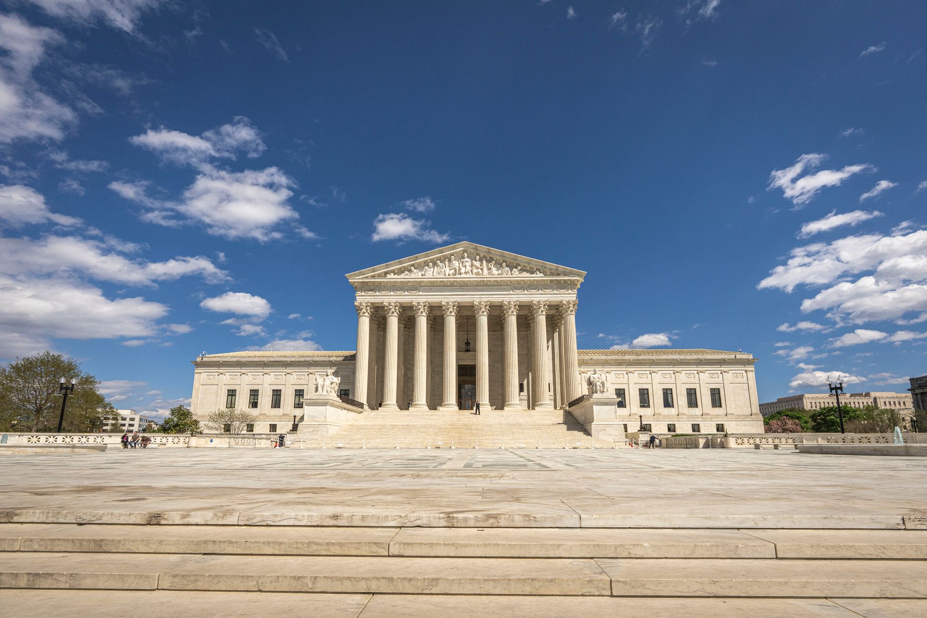 exterior of the Marriner S. Eccles Federal Reserve Building in Washington D.C. on a clear morning, its neoclassical stone facade visible against a pale blue sky