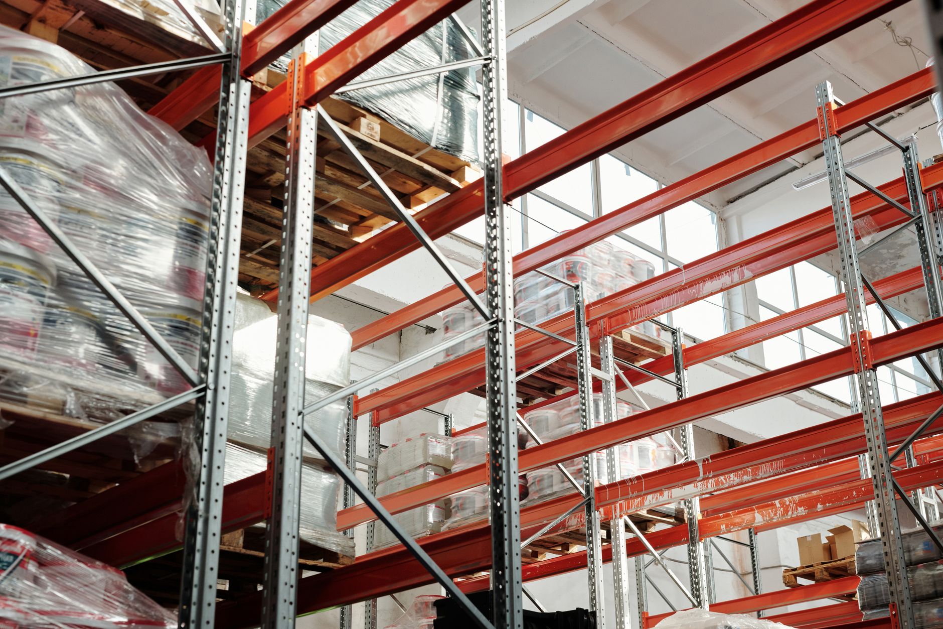 rows of gold bullion bars stacked on vault shelves under industrial lighting in a secure storage facility